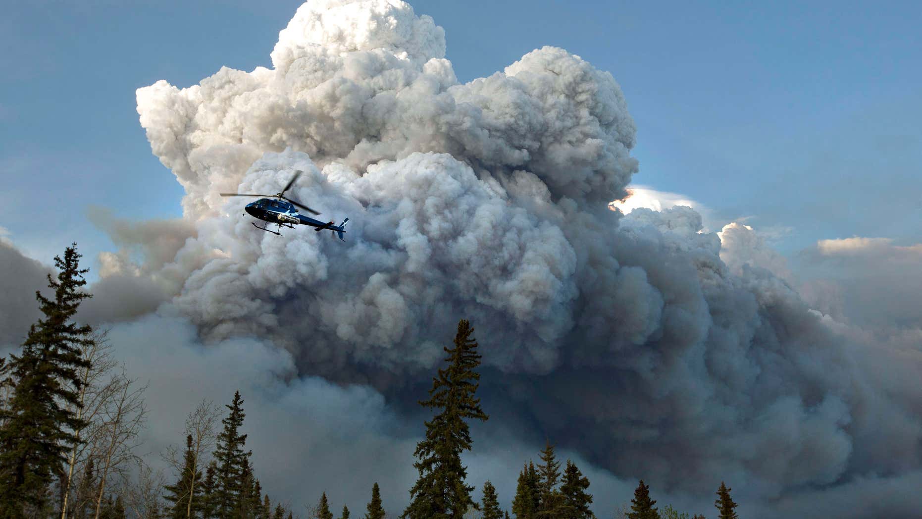 May 4, 2016: A helicopter flies past a wildfire in Fort McMurray, Alberta.