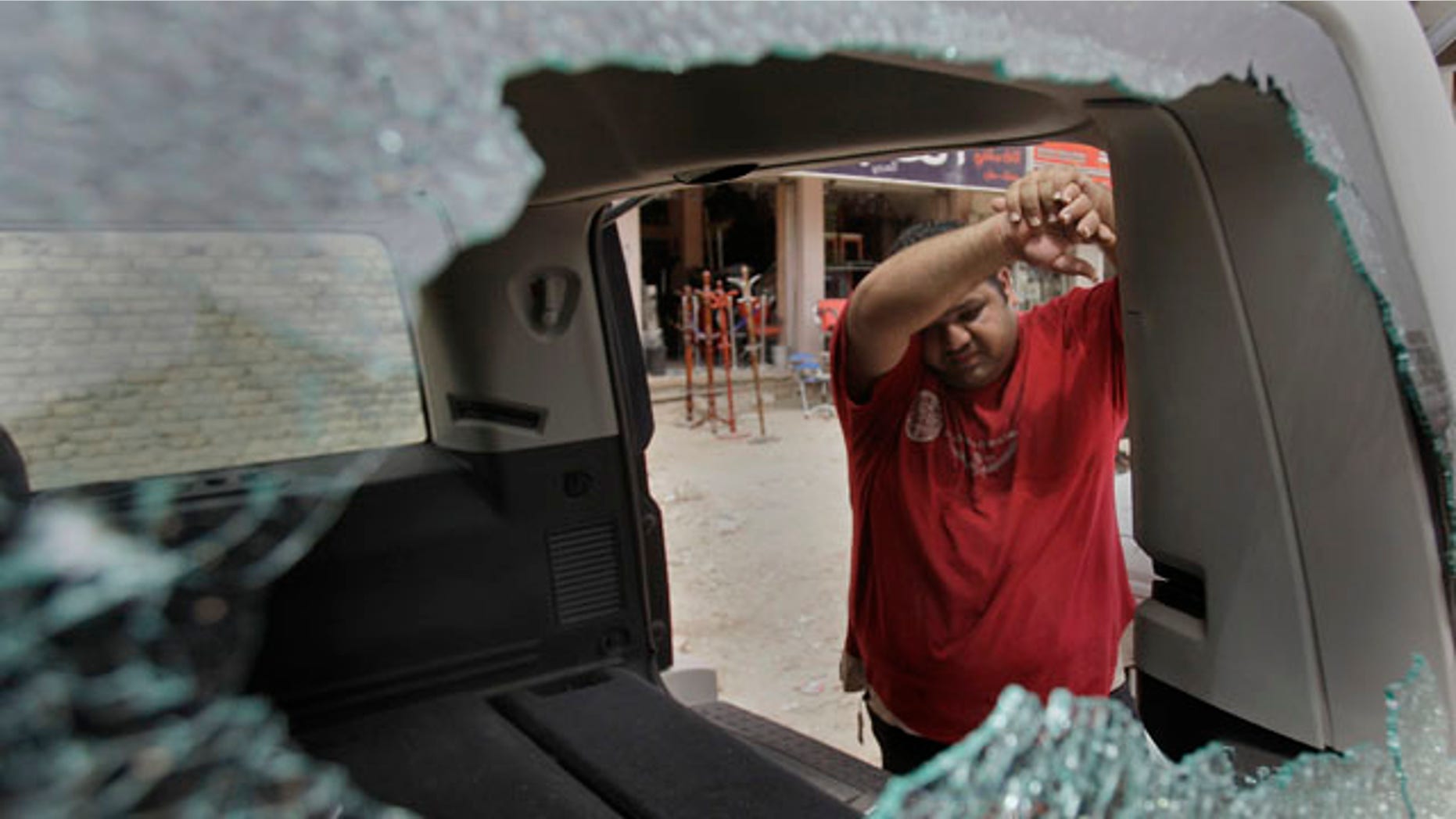 An Iraqi man inspects his damaged car at the site of a roadside bomb attack targeting a police patrol, killing and wounding a few civilians, police said, in central Baghdad, Iraq, Thursday, May 5, 2011. (AP Photo/Khalid Mohammed)