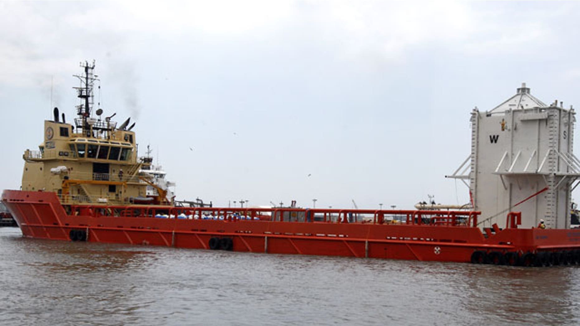 The barge Joe Griffin turns around in a channel after a crane loaded a chamber, right, that will be used to help contain oil leaking from the Deepwater Horizon oil drilling platform, in Port Fourchon, La.