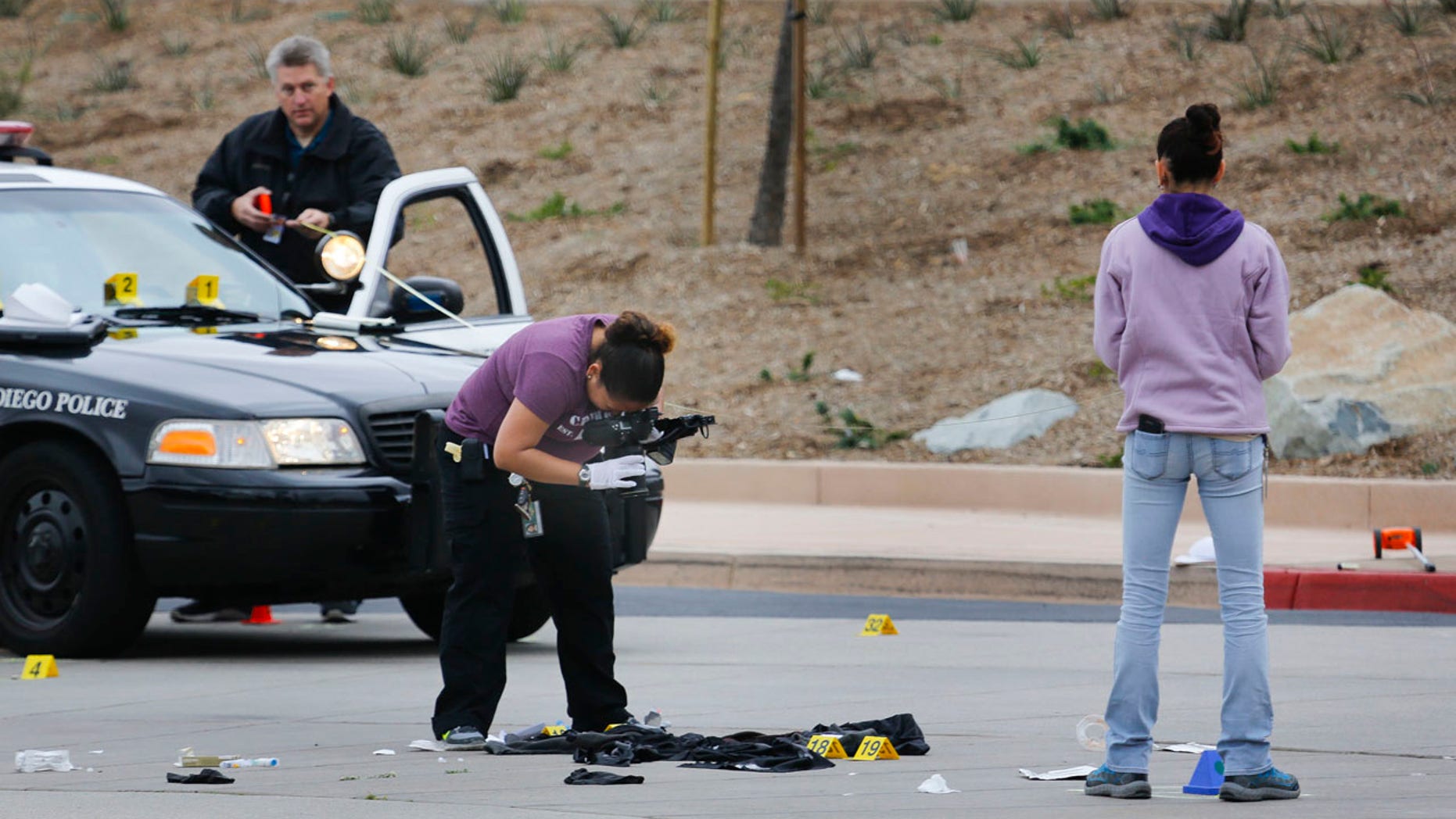 Members of the San Diego Police Department collect evidence at the scene of a fatal police officer involved shooting of a 15-year-old boy in one of the parking lots in front of Torrey Pines High School, early Saturday morning.
