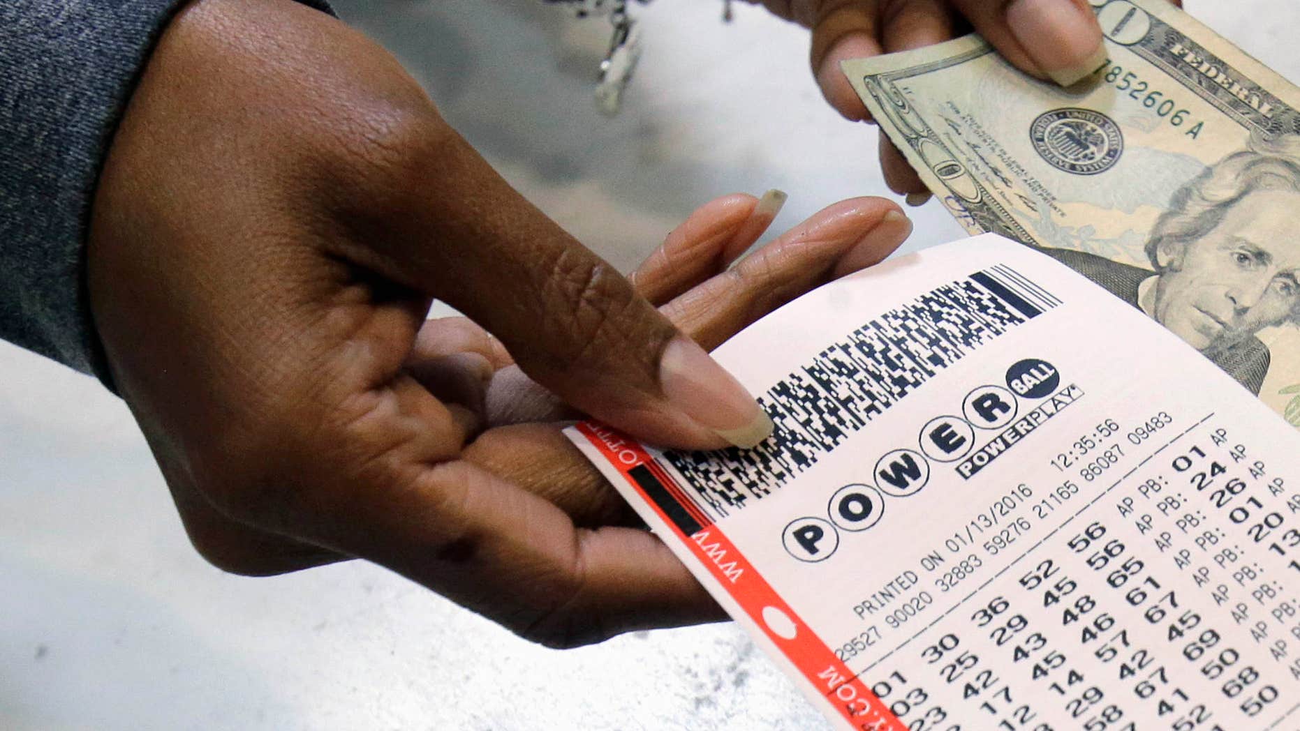 FILE - In this Jan. 13, 2016 file photo, a clerk hands over a Powerball ticket for cash at Tower City Lottery Stop in Cleveland.