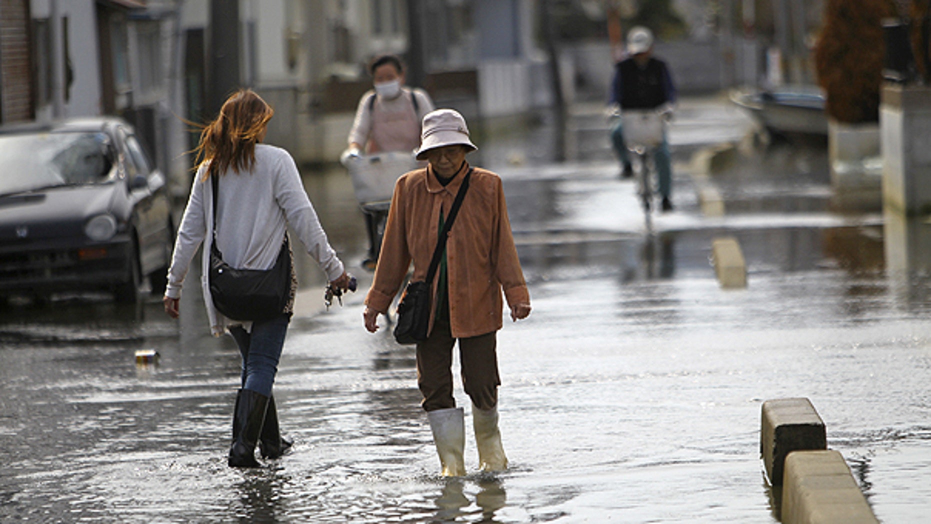 May 3: esidents stroll in a flooded street in Ishinomaki, Miyagi Prefecture, Japan. The area in this part of the city sunk nearly 2 feet 7 inches (0.8 meter) following the March 11 earthquake and tsunami.