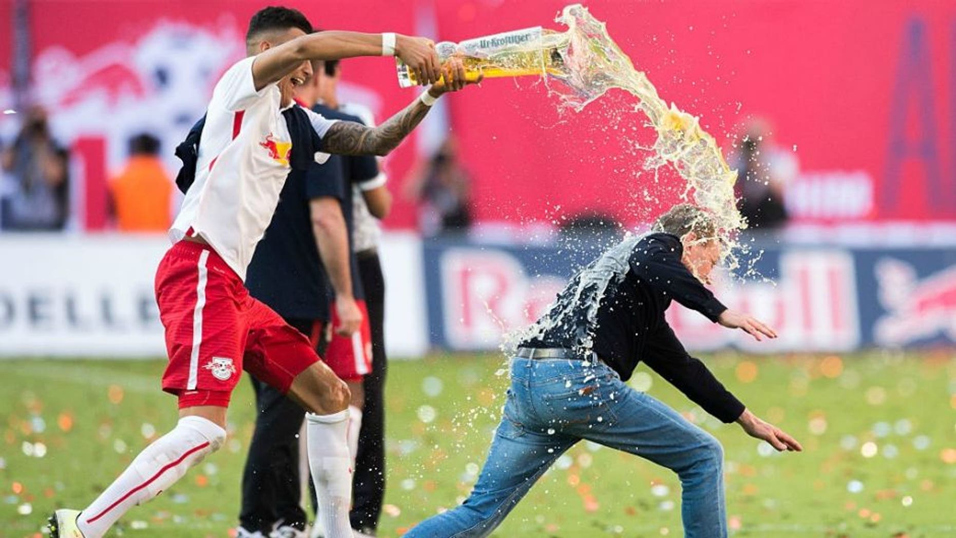 Leipzig��s Davie Selke (L) pours beer over headcoach Ralf Rangnick after the German second division Bundesliga football match between RB Leipzig and Karlsruher SC at the Red Bull Arena in Leipzig, eastern Germany, on May 8, 2016. Leipzig won the match 2-0 and will be promoted to the first division Bundesliga next season. / AFP / Robert MICHAEL (Photo credit should read ROBERT MICHAEL/AFP/Getty Images)