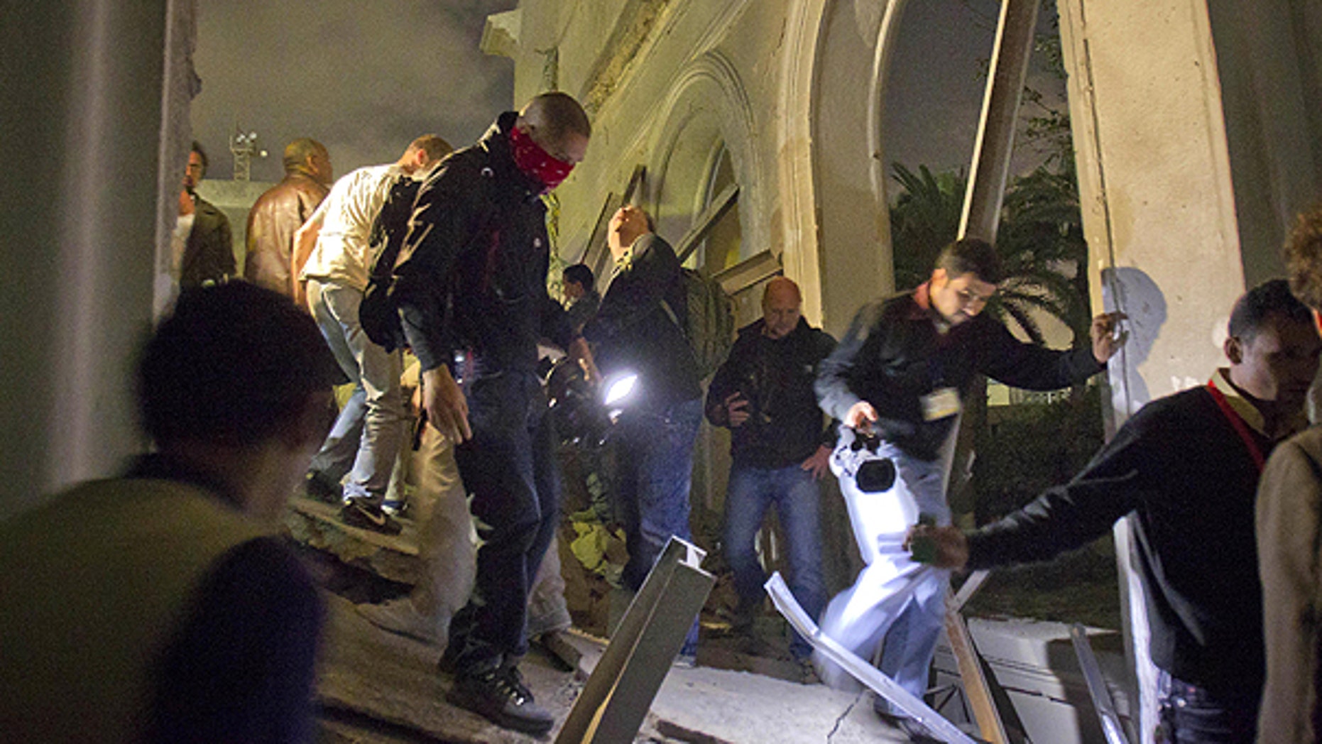 May 10: In this photo taken on a government organized tour, Libyan government officials and the media move through ruins of an official building following an air strike in Tripoli, Libya.
