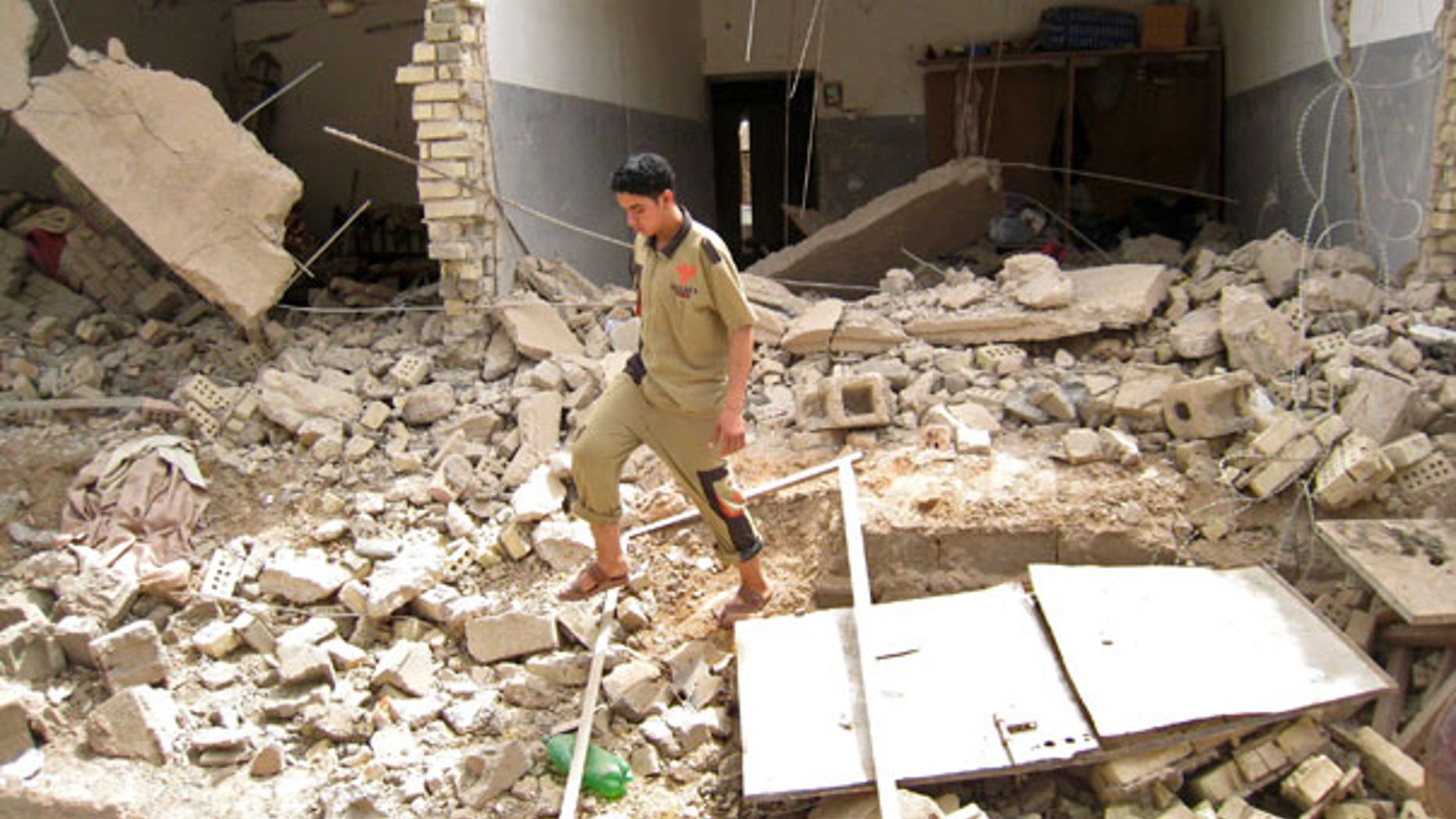May 10: An Iraqi man walks through rubble at the site of a bombing that targeted police in Fallujah, Iraq (AP).