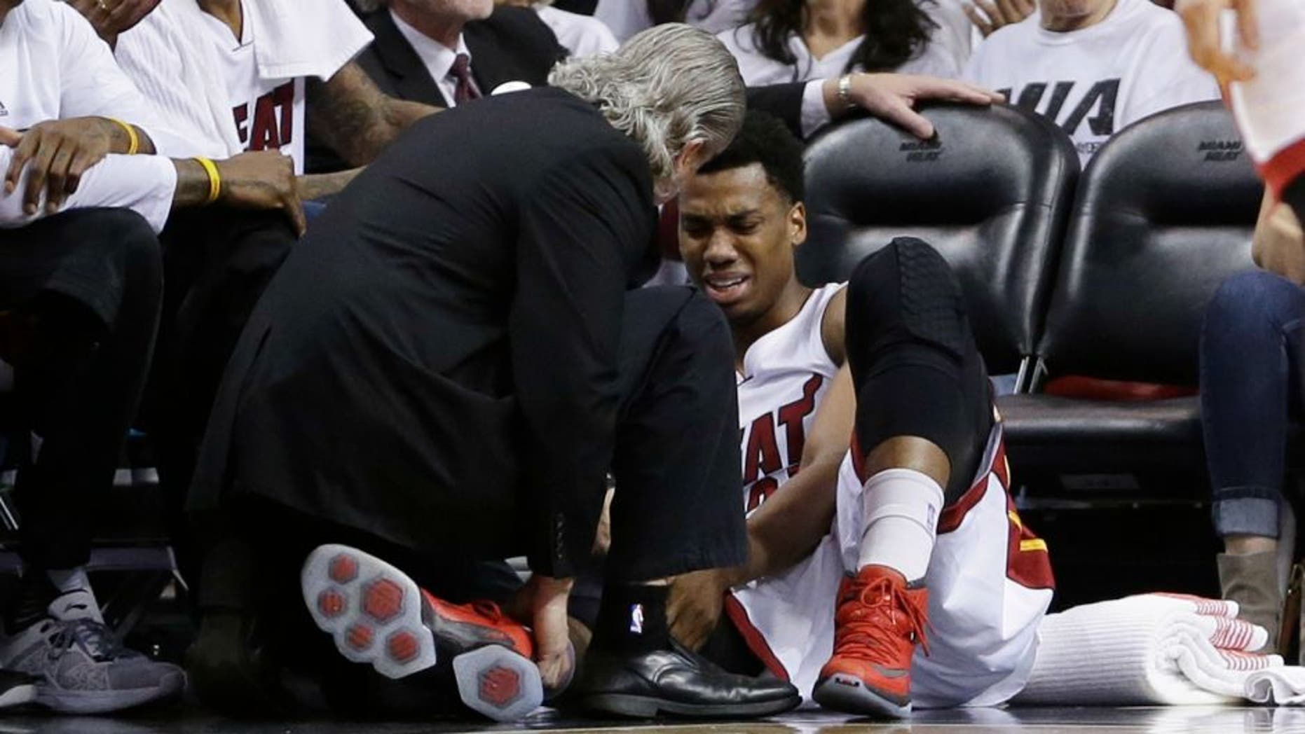Miami Heat center Hassan Whiteside (21) is attended by a team member after he was injured during the first half of Game 3 of an NBA second-round playoff basketball series against the Toronto Raptors, Saturday, May 7, 2016, in Miami. (AP Photo/Alan Diaz)