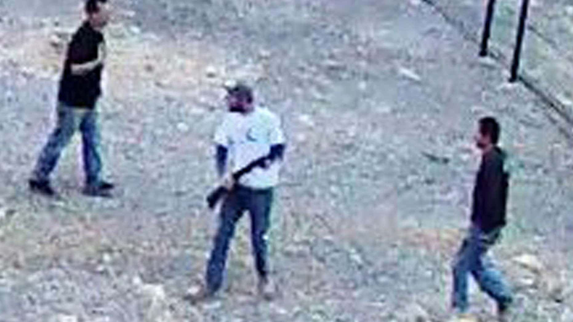 In this still image taken from security video on Saturday, April 30, 2016 and released by the National Park Service, three men inside the perimeter fence at the edge of Devils Hole in Death Valley National Park, Nev.
