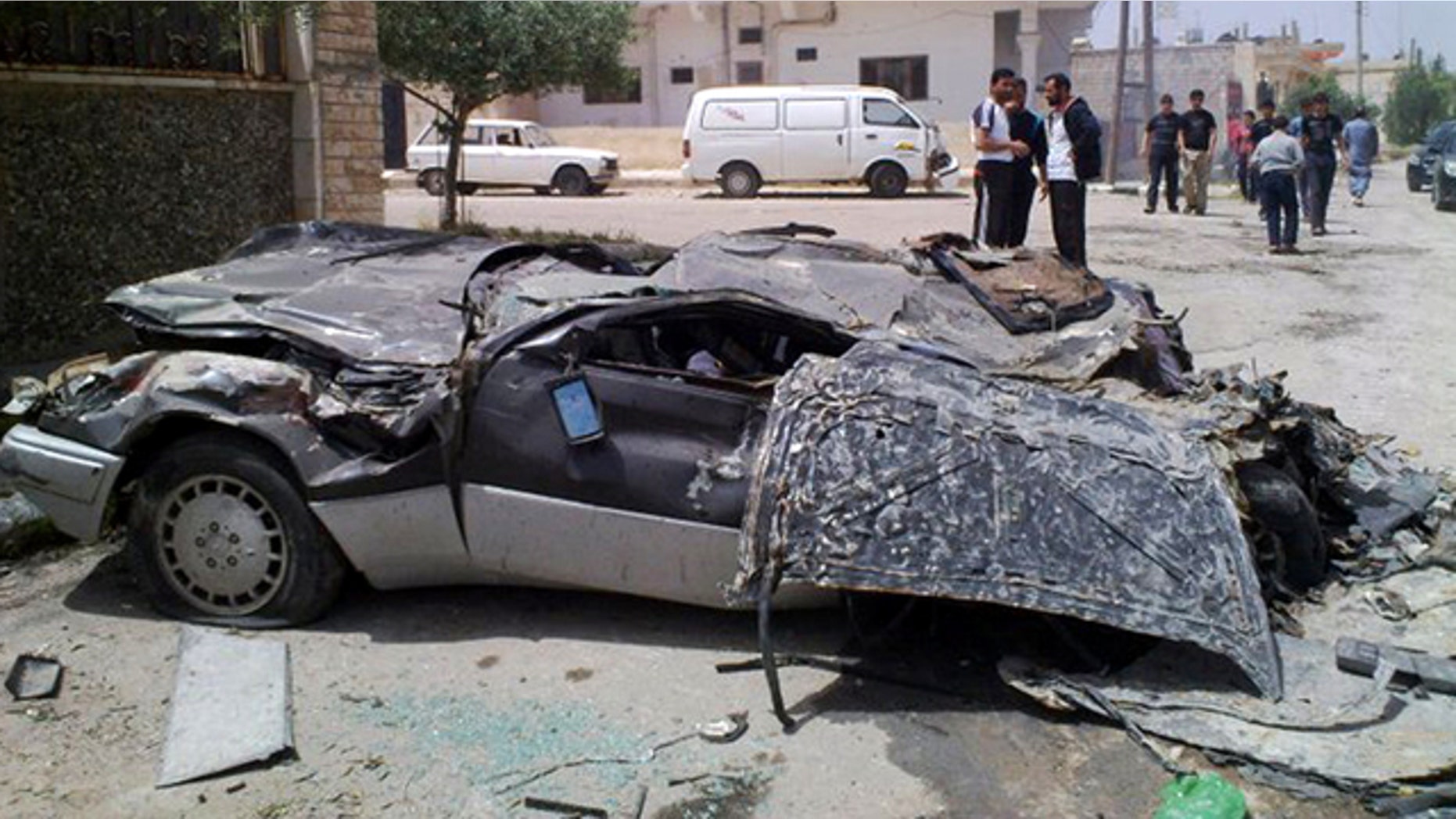 May 11: In this undated citizen journalism image made on a mobile phone and acquired by the AP, Syrians gather near a damaged car in the southern city of Daraa, Syria.
