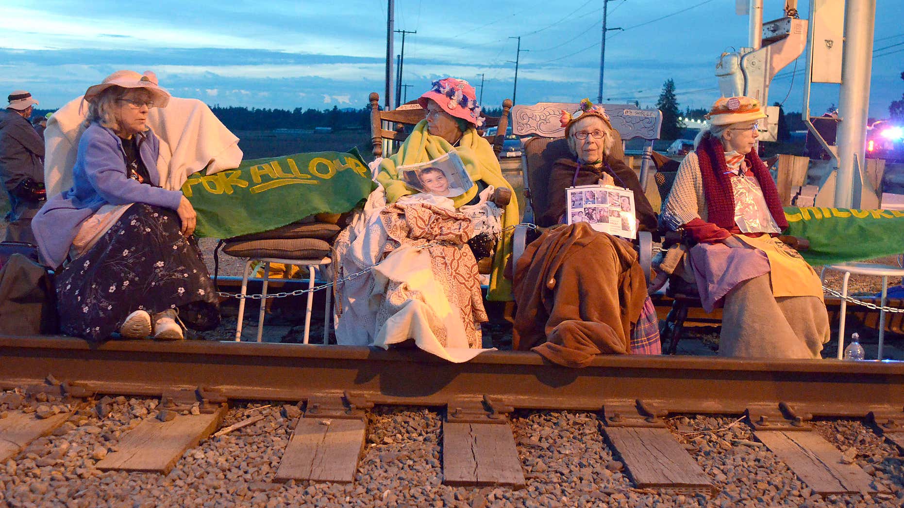 Members of the Seattle Raging Grannies sit in their rocking chairs chained together on the Burlington-Northern Railroad tracks at Farm to Market Road in Skagit County on Friday evening, May 13, 2016, in Burlington, Wash.