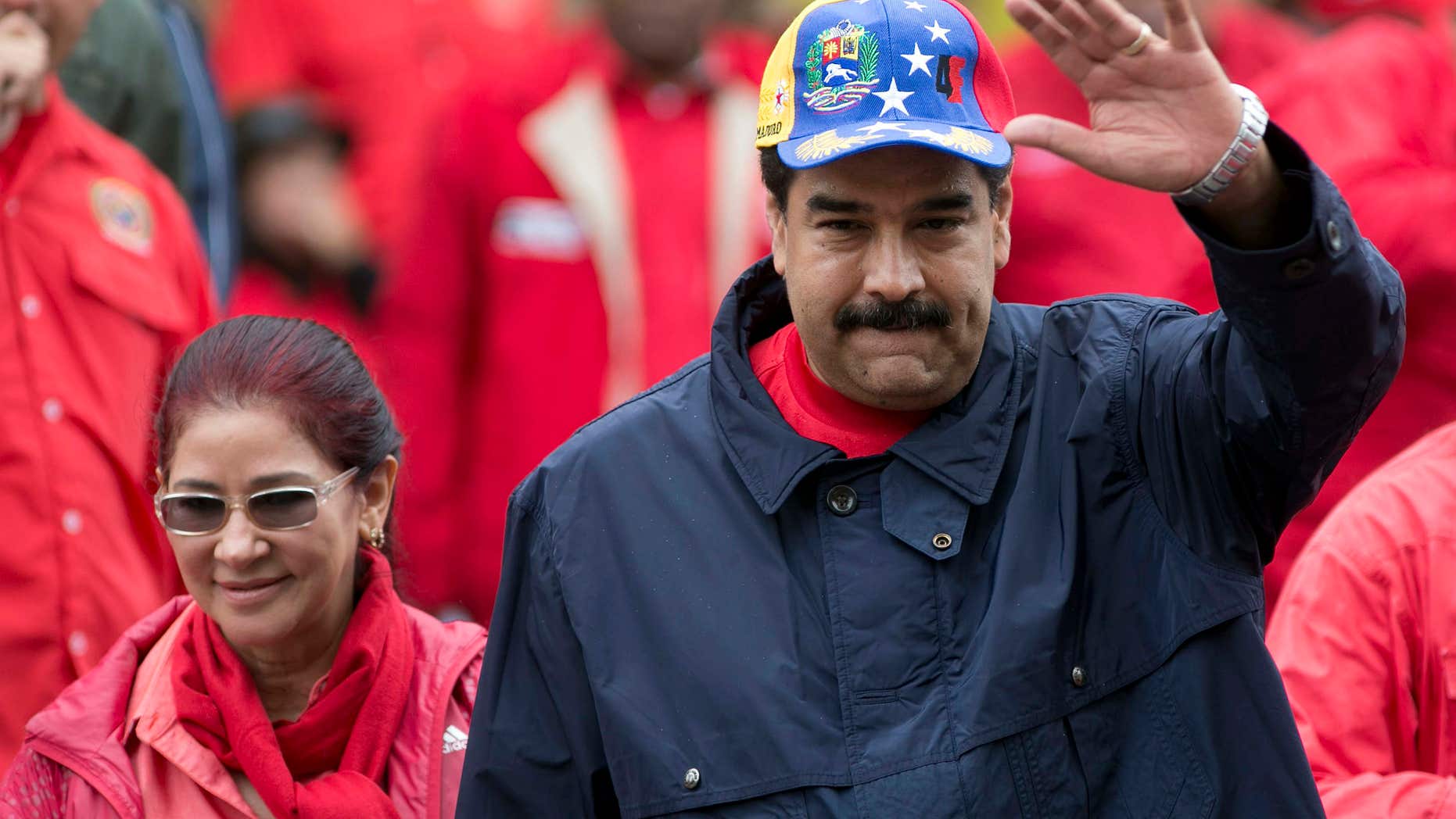 FILE - In this May 1, 2016 file photo, Venezuela's President Nicolas Maduro waves to supporters alongside first lady Cilia Flores during a labor day march in Caracas, Venezuela.