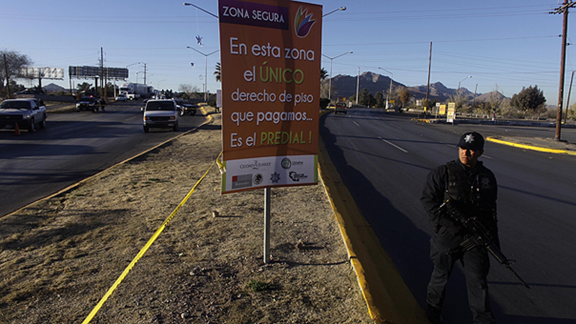 In this Dec. 13, 2010 file photo, a police officer walks beside a cordon for a crime scene in a heavily guarded commercial 'safe' zone in Ciudad Juarez, Mexico.