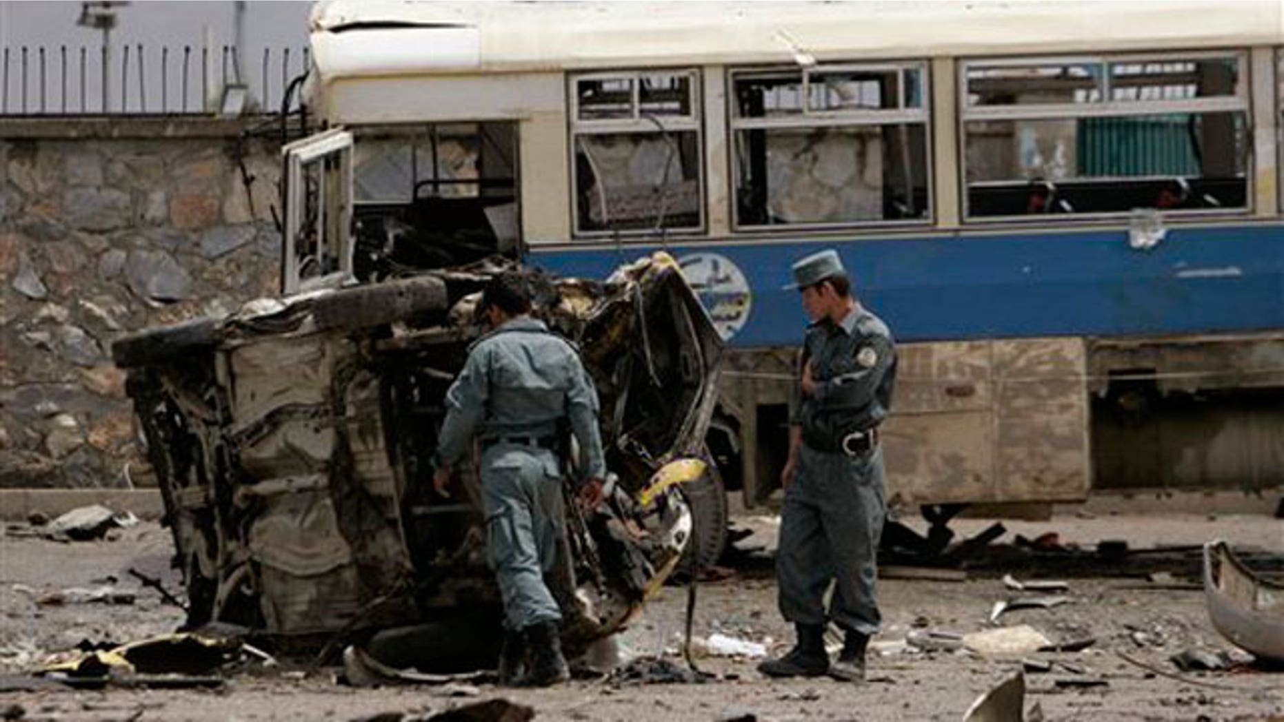 May 18: Afghan policemen look at the mangled remains of a vehicle after an attack in Kabul, Afghanistan.