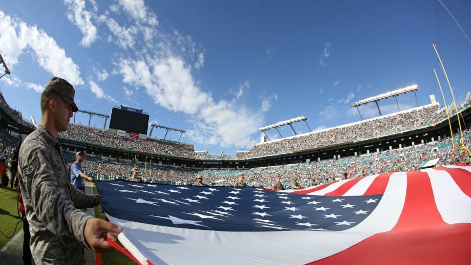 of the game at Sun Life Stadium on November 22, 2015 in Miami Gardens, Florida.,MIAMI GARDENS, FL - NOVEMBER 22: Memebers of the US Armed Forces hold an American Flag on the field for the singing of God Bless America during the second quarter of the game between the Miami Dolphins and the Dallas Cowboys at Sun Life Stadium on November 22, 2015 in Miami Gardens, Florida. (Photo by Rob Foldy/Getty Images)