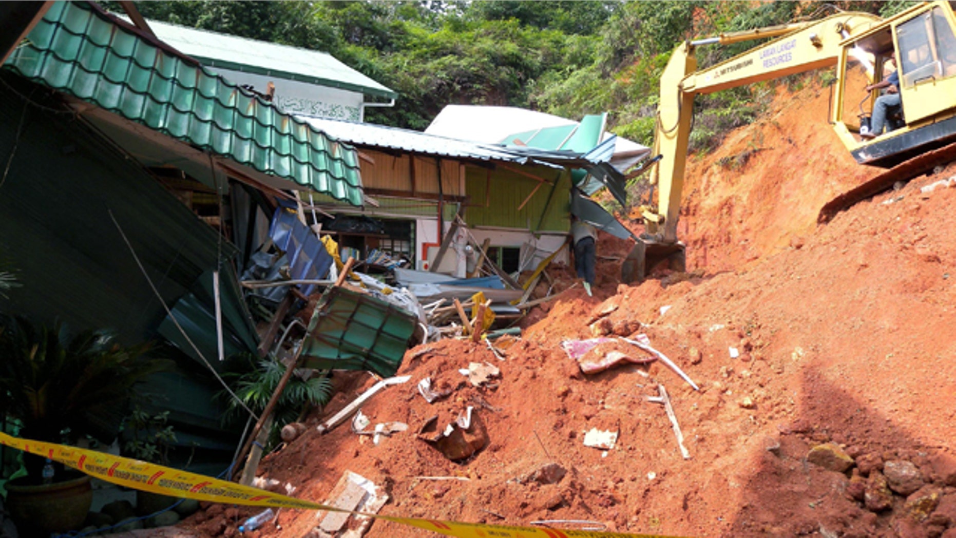 May 21: A rescuer uses a construction machine to search for the bodies believed to be buried by a landslide in Hulu Langat in central Selangor state, outside Kuala Lumpur, Malaysia.