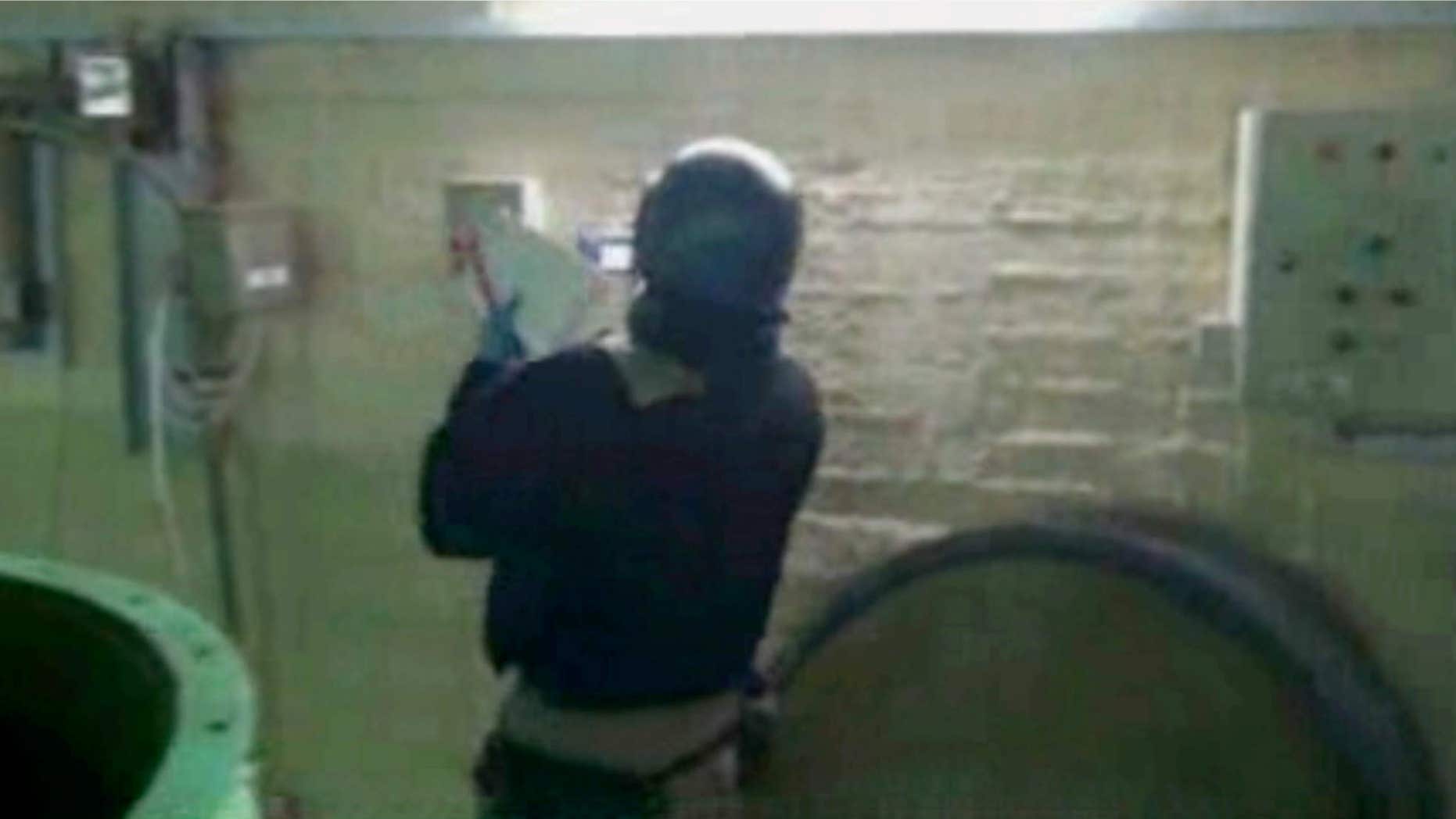 Oct. 8, 2013: This file image made from video broadcast on Syrian State Television, purports to show a chemical weapons expert taking samples at a chemical weapons plant at an unknown location in Syria.
