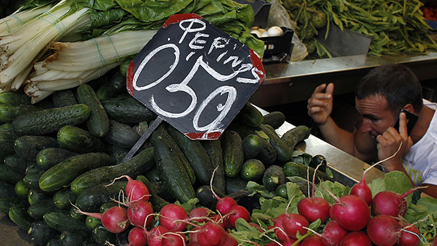 May 30: A market seller speaks on his cell phone behind a display of cucumbers and other vegetables in Malaga, southern Spain.