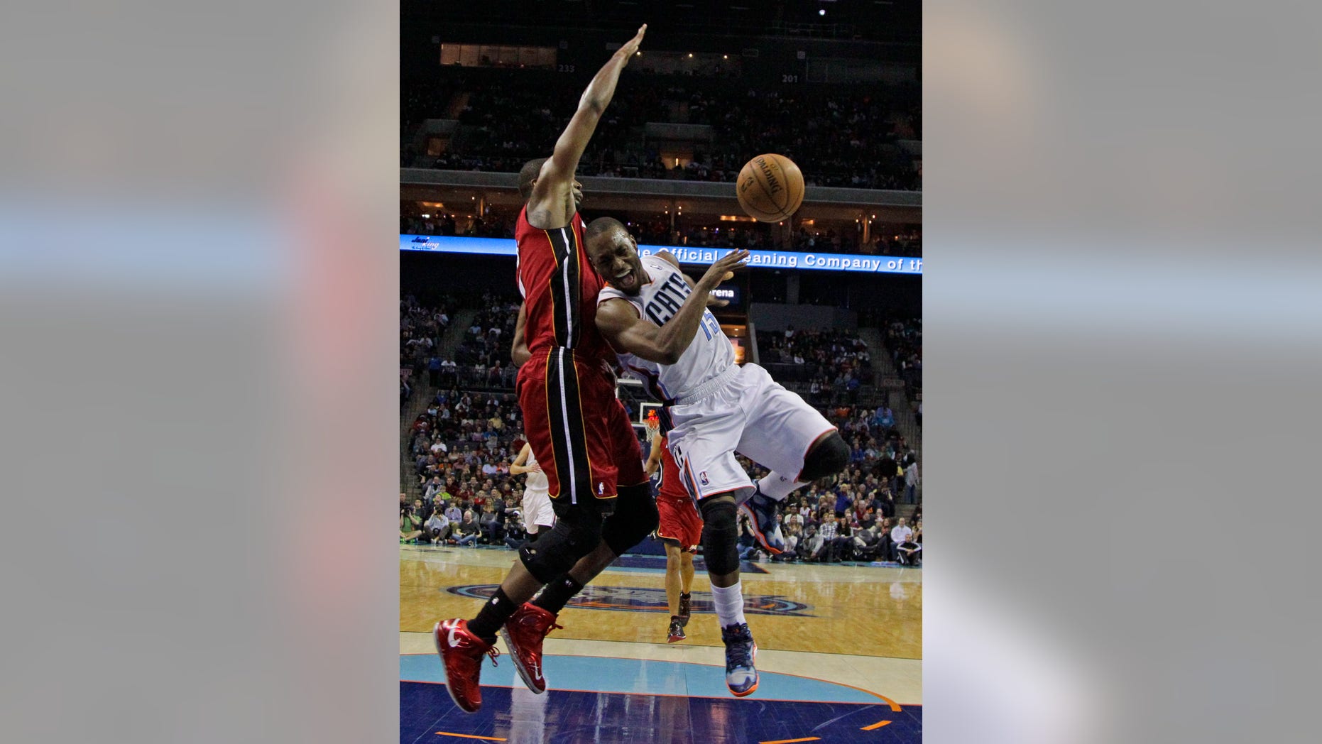 Charlotte Bobcats' Kemba Walker, right, loses the ball as he drives against Miami Heat's Chris Bosh, left, during the second half of an NBA basketball game in Charlotte, N.C., Saturday, Jan. 18, 2014. Walker was injured on the play. The Heat won 104-96 in overtime. (AP Photo/Chuck Burton)