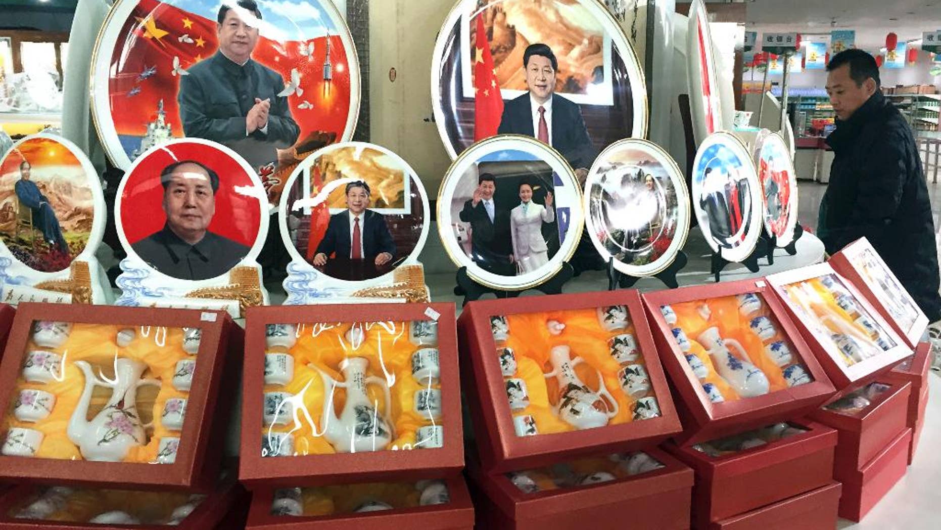 In this photo taken Friday, Dec. 30, 2016, a Chinese man walks past ceramic plates with images of Chinese President Xi Jinping displayed at a rest stop near Beijing. During his annual New Year Eve's speech, Chinese President Xi Jinping says his government will continue to focus on poverty alleviation at home and resolutely defending China's territorial rights on the foreign front. (AP Photo/Ng Han Guan)