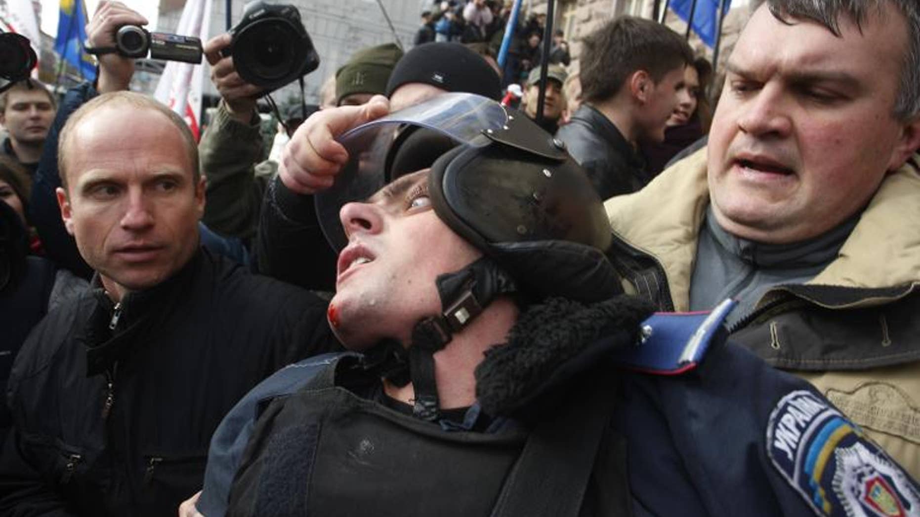 A Ukrainian opposition activist grabs the helmet of a riot policeman during clashes in Kiev, on October 2, 2013