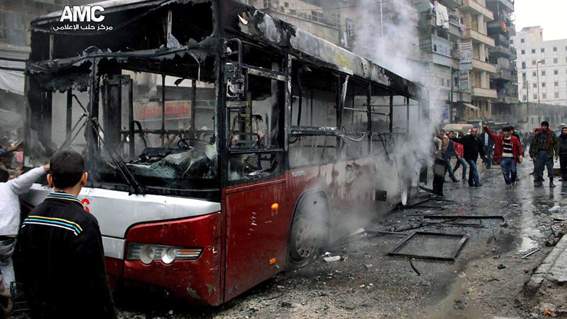 This citizen journalism image provided by Aleppo Media Center AMC which has been authenticated based on its contents and other AP reporting, shows Syrians inspecting a burnt bus after a missile fired by Syrian government aircraft hit the vehicle in the rebel-held neighborhood of al-Bab in Aleppo, Syria, Tuesday, Dec. 31, 2013. The bus was full of people when it was struck, setting it on fire and killing several people, activists said.. (AP Photo/Aleppo Media Center AMC)