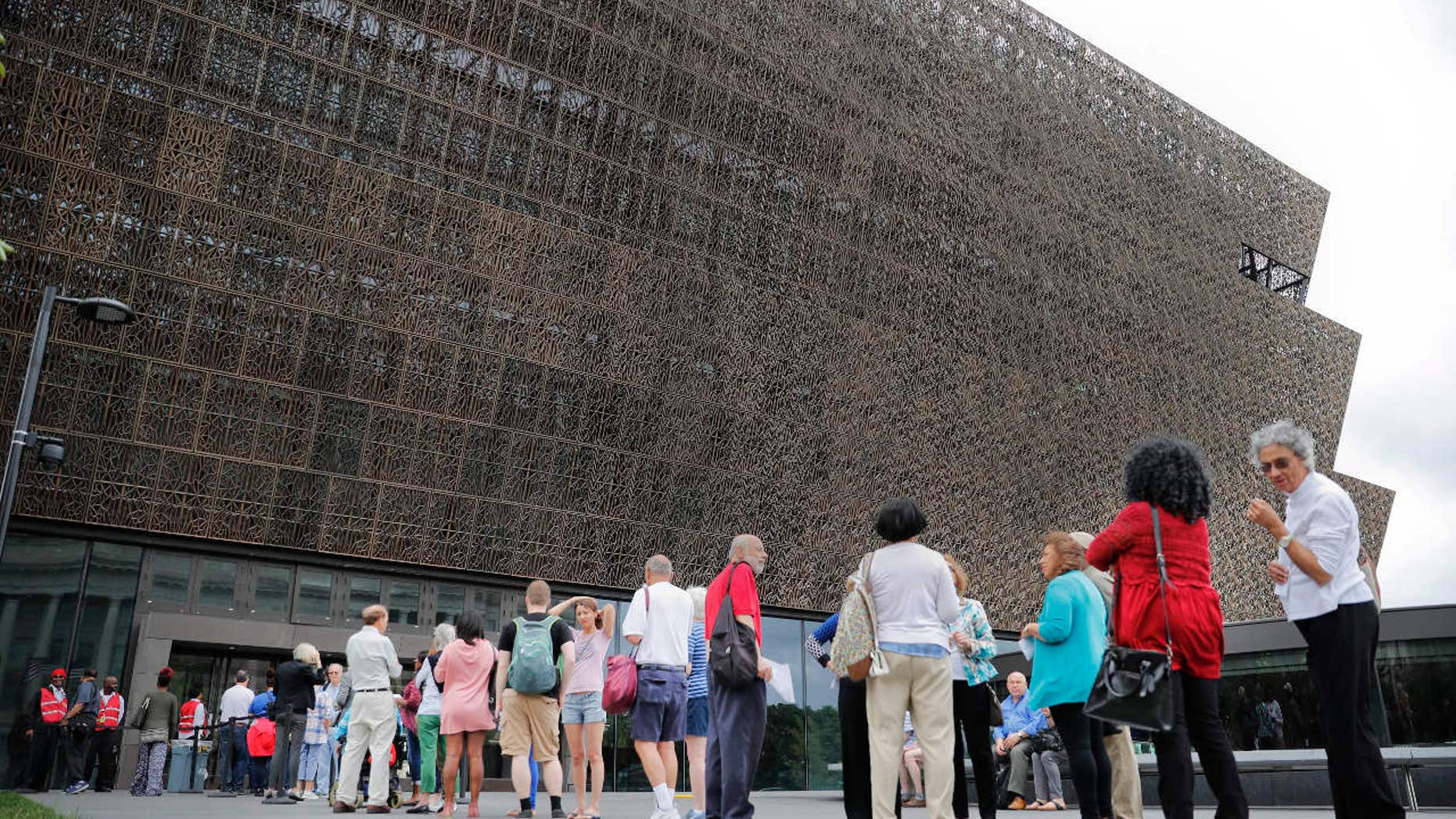 FILE- In this May 1, 2017, file photo, people wait in line to enter the Smithsonian National Museum of African American History and Cultural on the National Mall in Washington.