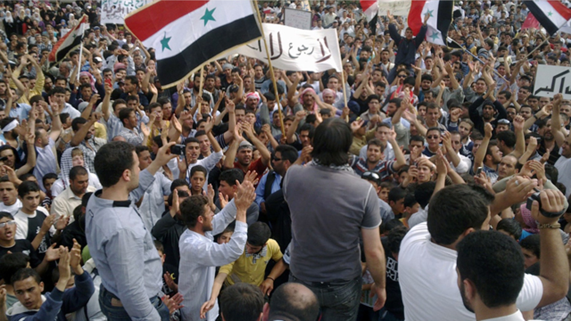 May 29: In this citizen journalism image made on a mobile phone and provided by Shaam News Network, Syrian anti-regime protesters carry national flags and banners during a rally in Talbiseh, in the central province of Homs, Syria.