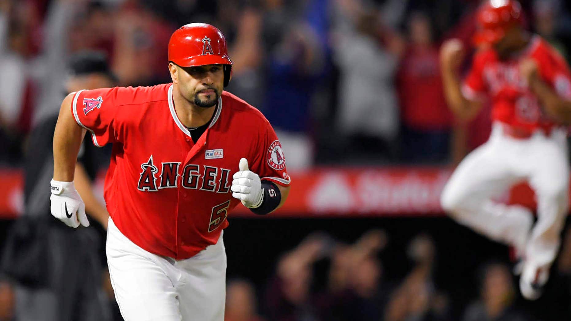 Los Angeles Angels' Albert Pujols, left, runs to first with a solo home run, the 600th homer of his career, while Ben Revere jumps in the background during the fourth inning of the team's baseball game against the Minnesota Twins, Saturday, June 3, 2017, in Anaheim, Calif.