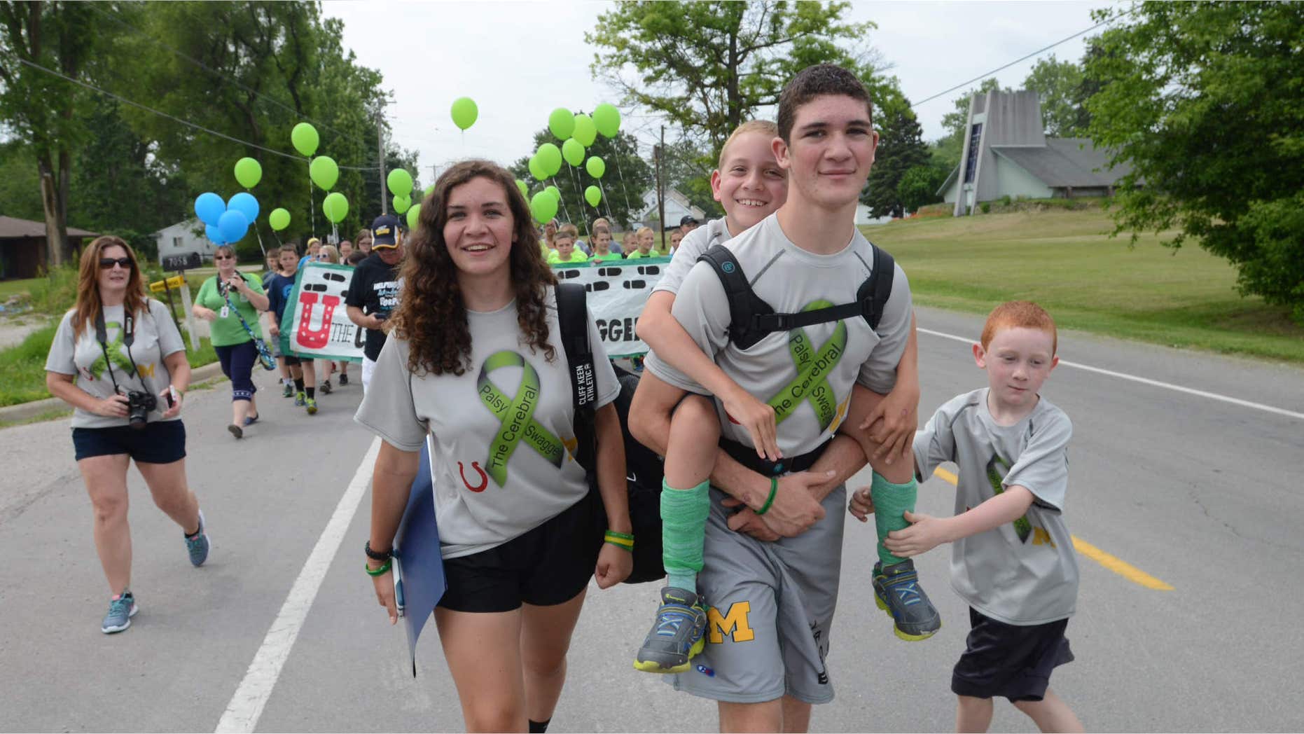 June 5, 2015: Braden Gandee rides aboard his brother Hunter's back who is walking along side sister, Kerragan and brother, Kellen as the Gandee family begins the 55 mile walk from Temperance, Mich., to Ann Arbor.