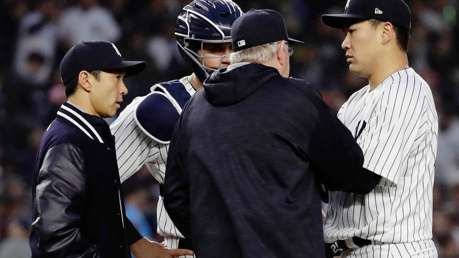 June 6, 2017: New York Yankees starting pitcher Masahiro Tanaka, of Japan, right, talks to catcher Gary Sanchez, second from left, pitching coach Larry Rothschild and translator Shingo Horie, left, during the fourth inning of a baseball game in New York.