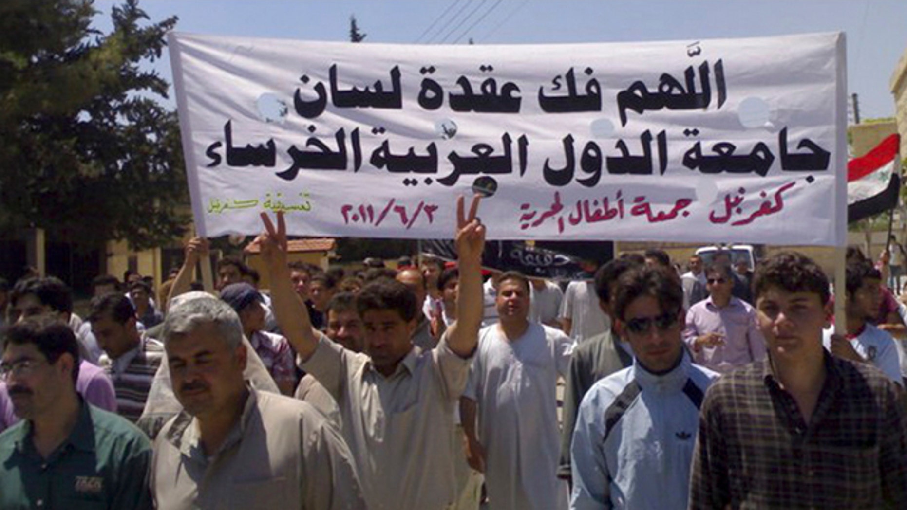 June 3: In this citizen journalism image made on a mobile phone and provided by Shaam News Network, Syrian protesters hold an Arabic banner as they march during a protest at the village of Kfar-Nebel, in the northen province of Edleb, Syria.