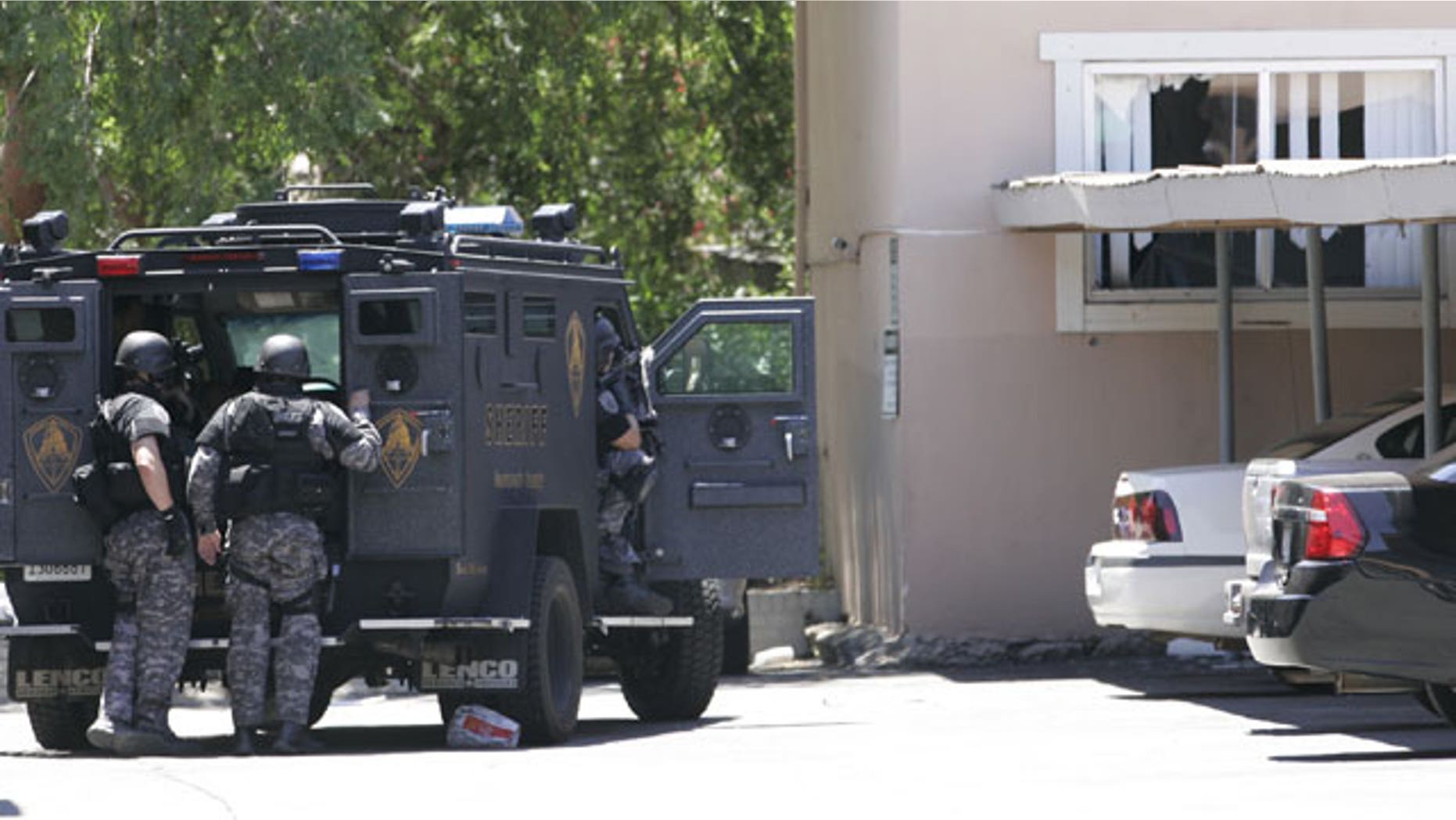 June 10: Law enforcement officers huddle behind an armored vehicle outside an apartment, window at right, during a standoff where an armed robbery suspect barricaded himself and a 1-year-old boy in Sacramento, Calif.