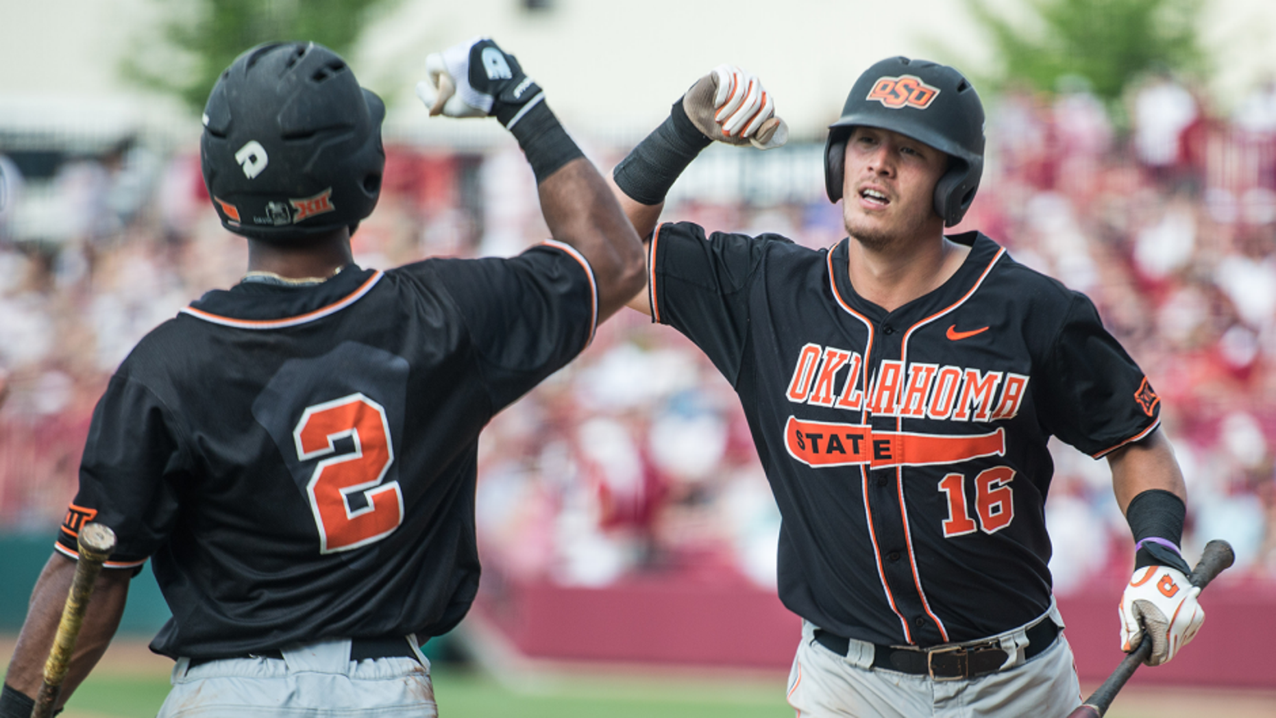 Oklahoma State catcher Collin Theroux (16) celebrates his ninth inning home run with teammate J.R. Davis (2) during an NCAA college baseball tournament super regional game against South Carolina, Saturday, June 11, 2016, in Columbia, S.C. Oklahoma State defeated South Carolina 5-1. (AP Photo/Sean Rayford)