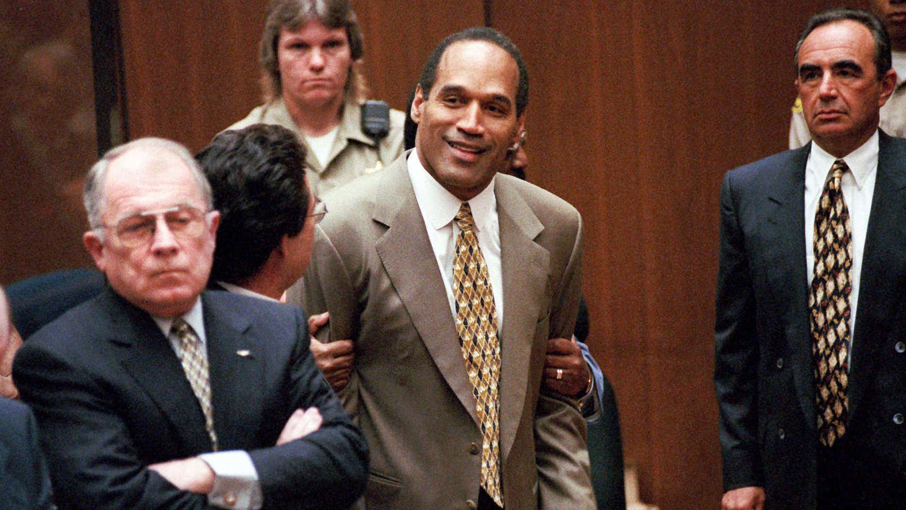 FILE - In this Oct. 3, 1995 file photo, O.J. Simpson, center, clenches his fists in victory after the jury said he was not guilty in the murders of his ex-wife Nicole Brown Simpson and her friend Ronald Goldman in a Los Angeles courtroom as attorneys F. Lee Bailey, left, and Robert Shapiro, right, look on.
