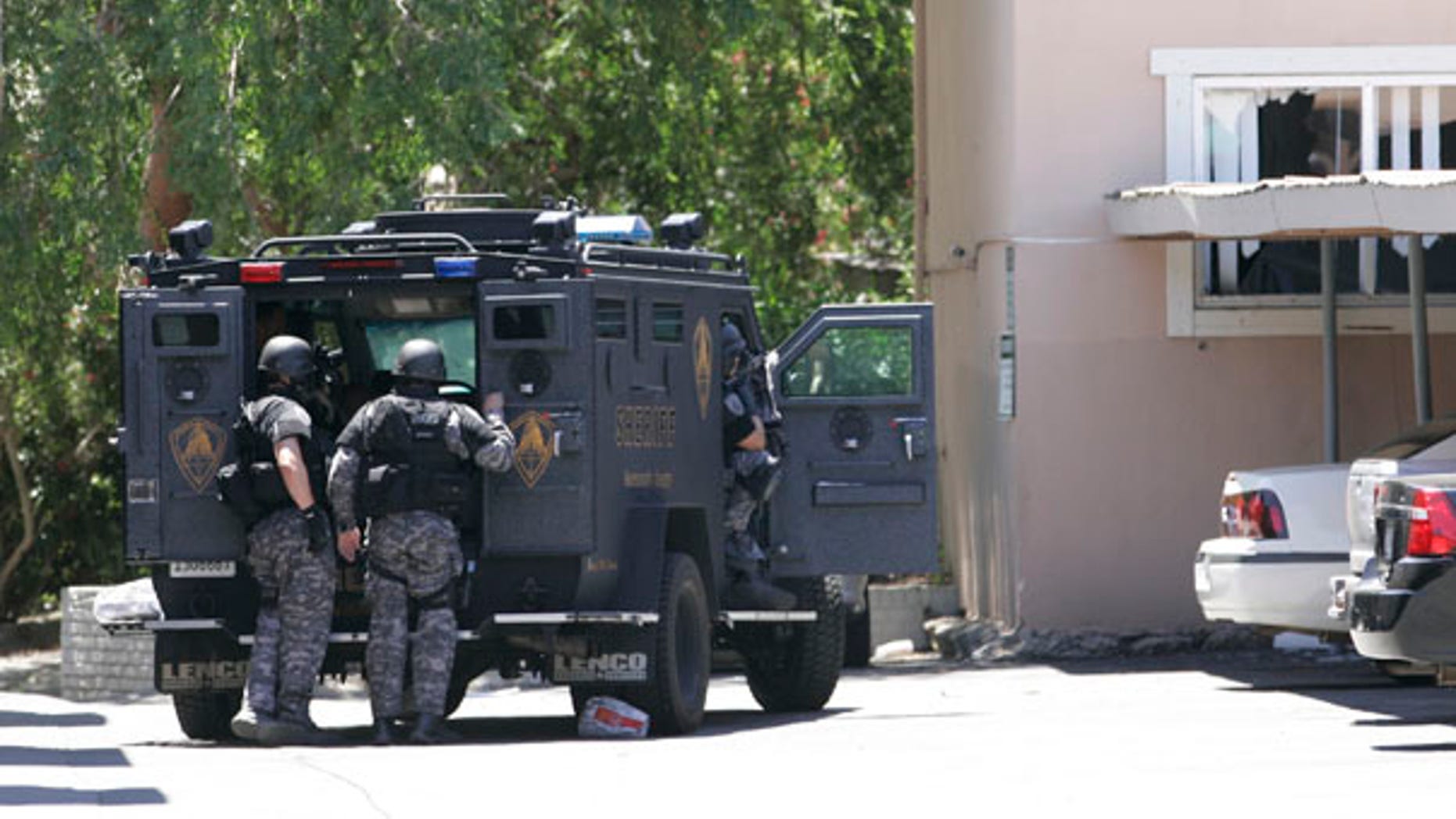 June 10: Law enforcement officers huddle behind an armored vehicle outside an apartment during day two of a hostage standoff as an armed robbery suspect barricaded himself and a 15-month-old boy in Sacramento, Calif.