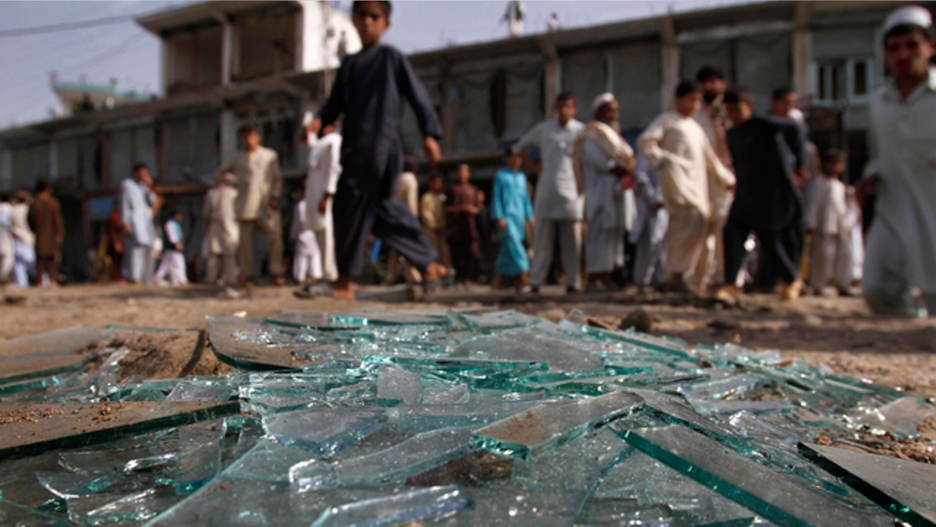June 11: Afghans walk pass the derbis at the site of a bomb explosion in Laghman province east of Kabul, Afghanistan.