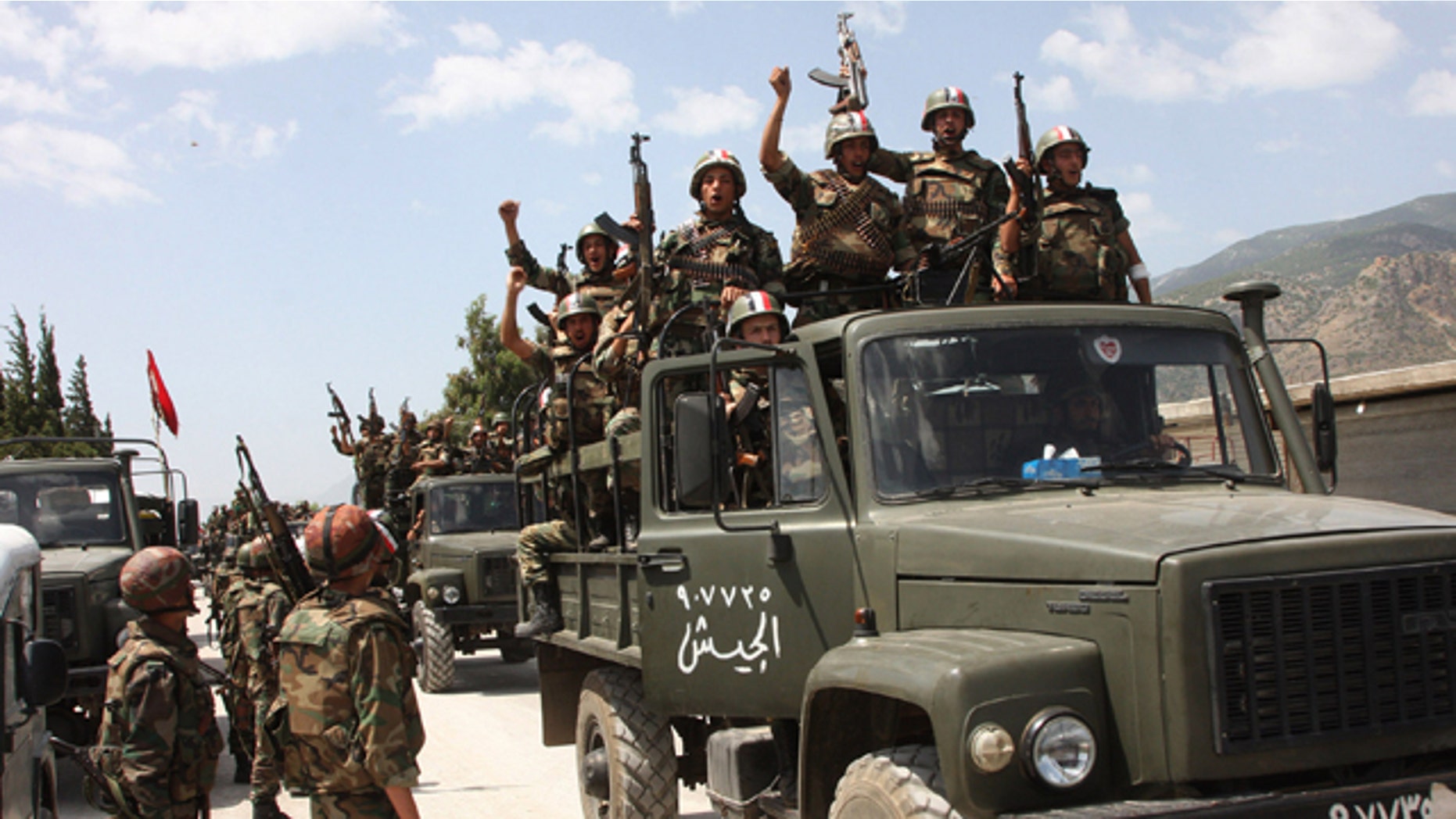June 10: In this photo taken during a government-organized visit for media, Syrian army soldiers standing on their military trucks shout slogans in support of Syrian President Bashar Assad, as they enter a village near the town of Jisr al-Shughour, north of Damascus, Syria.