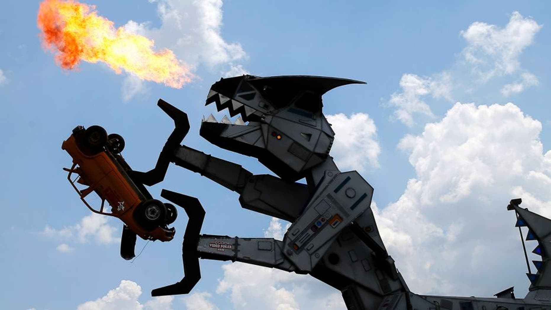 Robosaurus, a mechanical customized tractor trailer, is operated by IndyCar driver Juan Pablo Montoya and Shawn Pacheco, both located in the cockpit of the 40-foot-tall creation as it spews flames while destroying a small vehicle, Thursday, June 9, 2016, in Dallas. Montoya is scheduled to race in Saturday's Firestone 600 auto race at Texas Motor Speedway. (AP Photo/Tony Gutierrez)