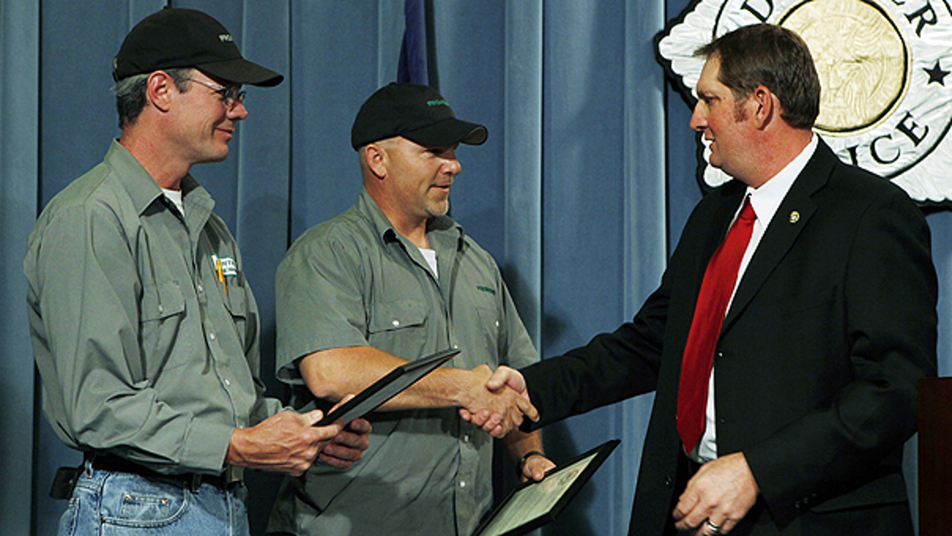 June 14: Frontier Airlines employees Mark Adams, left, and Kris Musil are congratulated by Detective Ed David during a news conference at Denver Police headquarters.