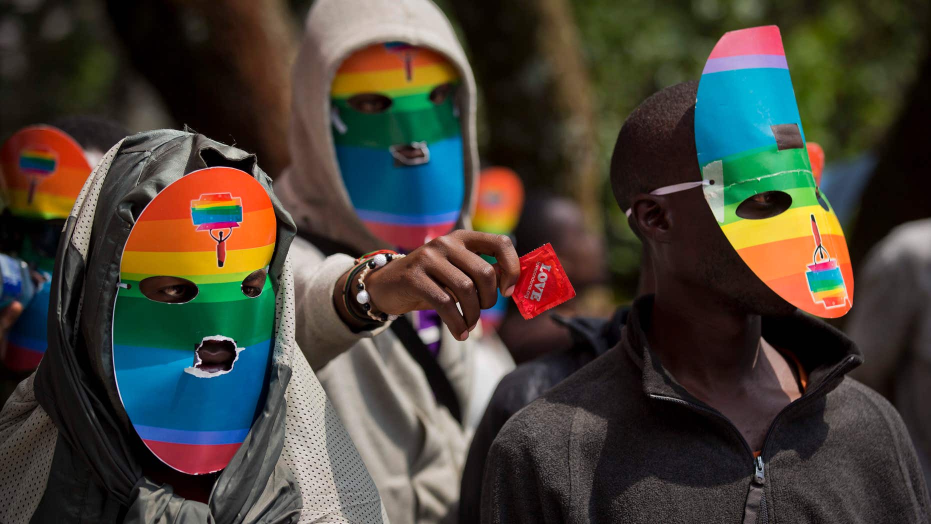 FILE - In this Monday, Feb. 10, 2014 file photo, Kenyan gays and lesbians and others supporting their cause wear masks to preserve their anonymity and one holds out a wrapped condom, as they stage a rare protest, against Uganda's increasingly tough stance against homosexuality and in solidarity with their counterparts there, outside the Uganda High Commission in Nairobi, Kenya.