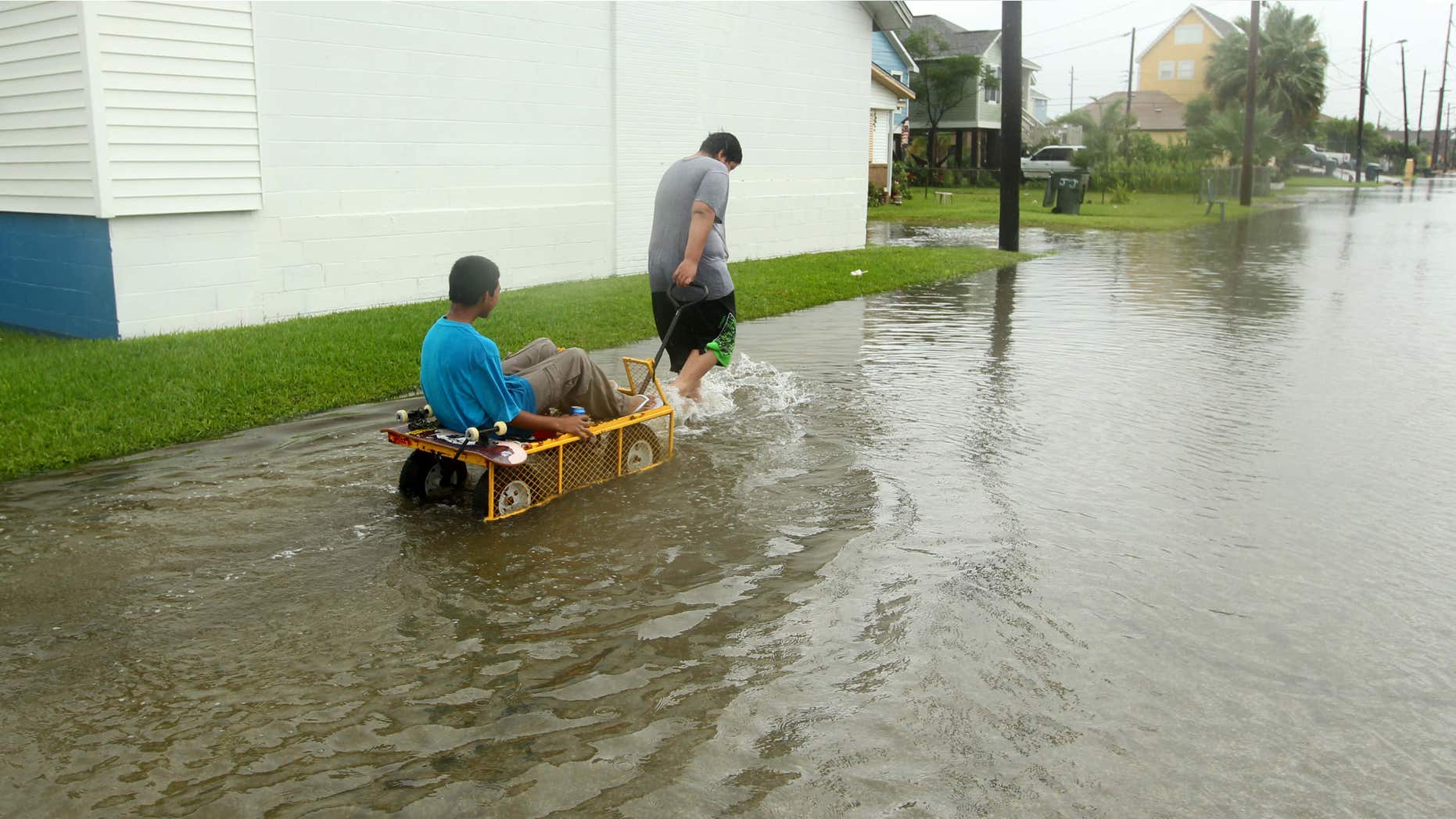 June 16, 2015: Manuel Martinez pulls Jesse McGehee through high water on Saladia Street in Galveston, Texas.