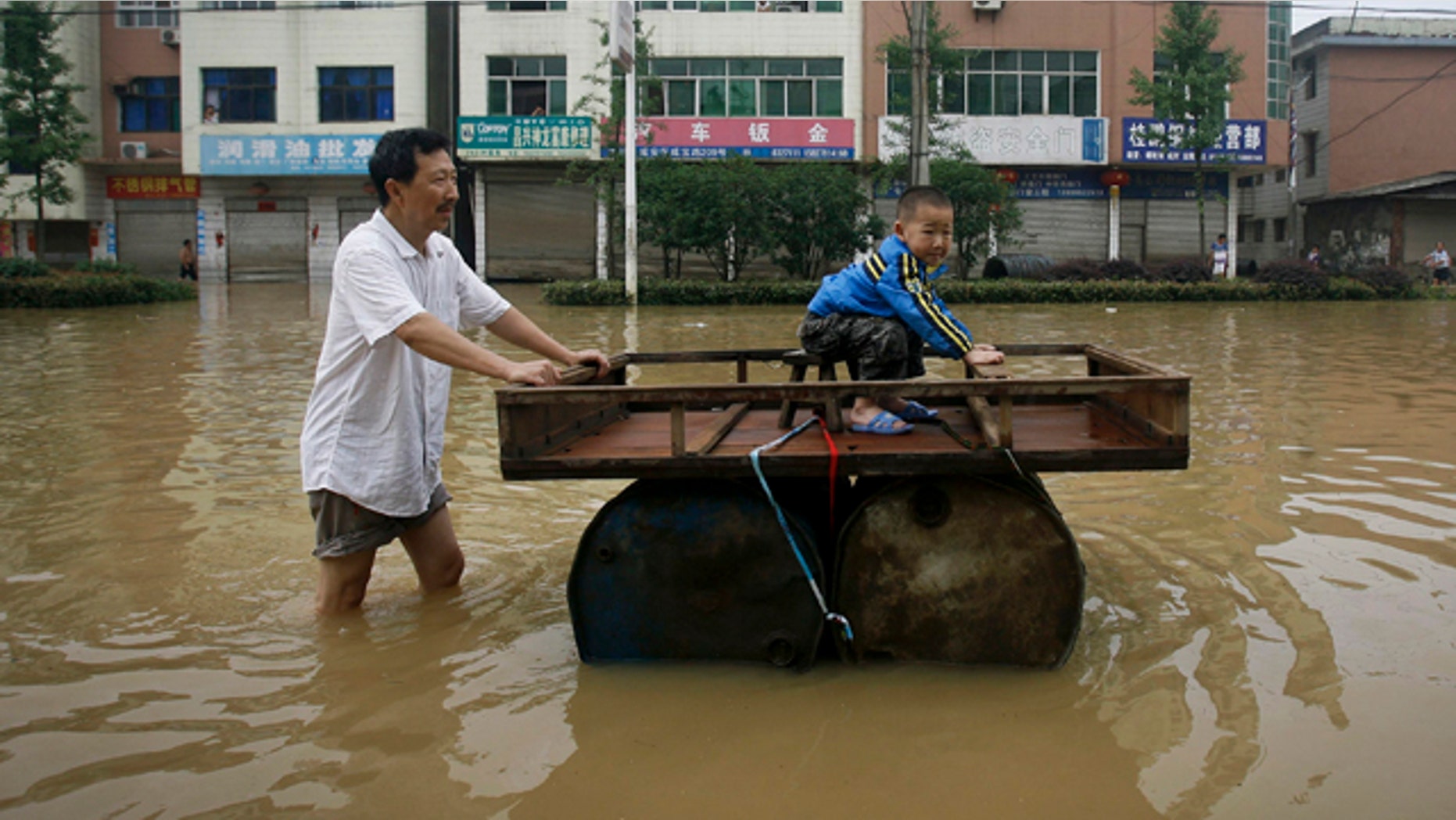 June 15: A Chinese man pushes a makeshift drum raft while a child sits on it in a flooded street in Xianing city in central China's Hubei province.