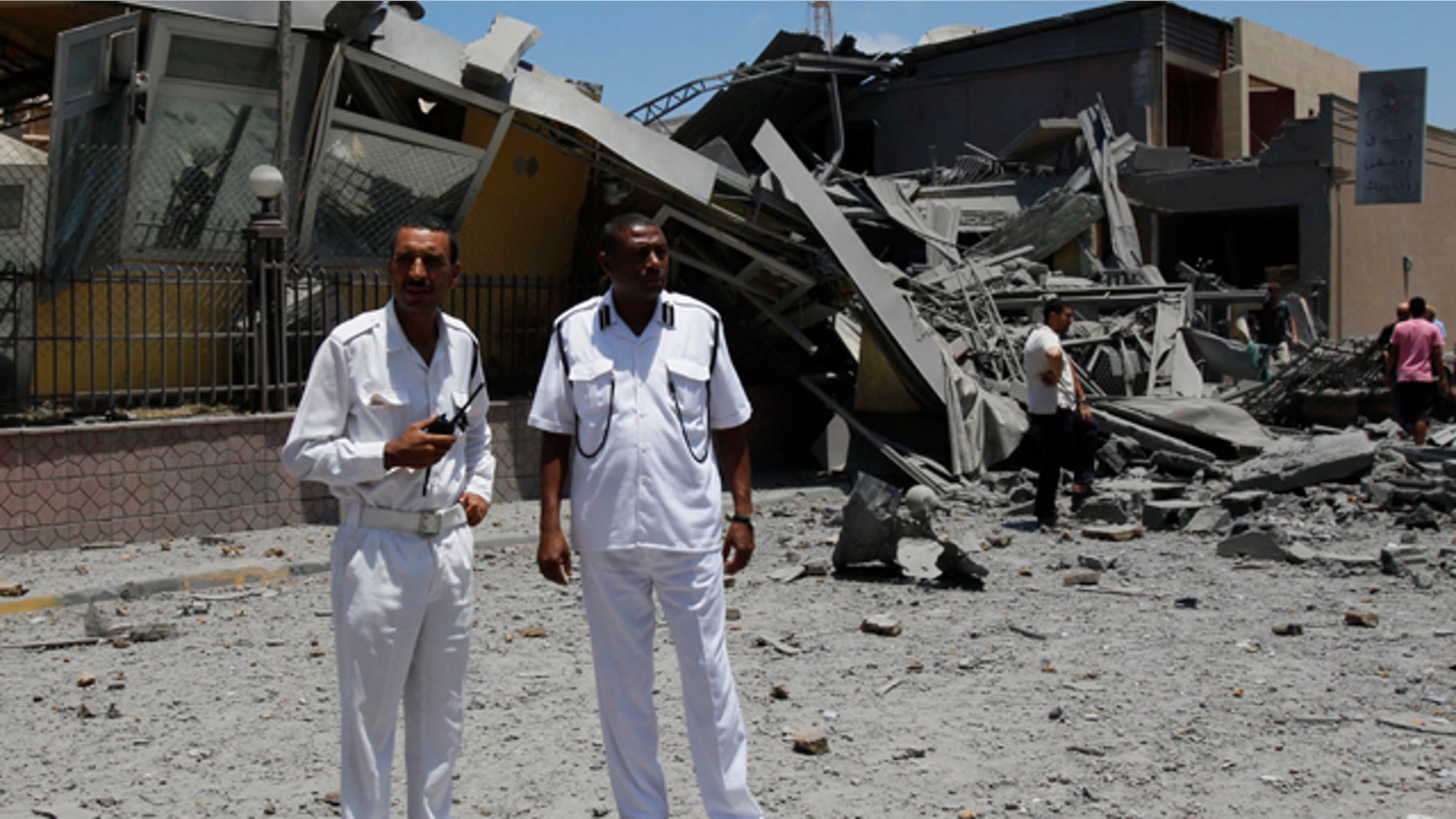 June 16: Libyan police officers stand next to a destroyed building in what officials said was a NATO airstrike at a hotel, in Tripoli, Libya.