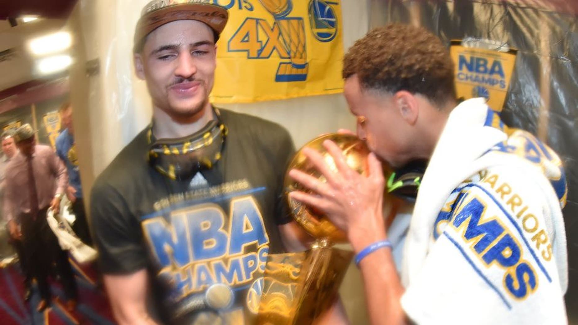 CLEVELAND, OH - JUNE 16: Klay Thompson #11 and Stephen Curry #30 of the Golden State Warriors celebrate with the Larry O'Brien Championship Trophy in the locker room after a victory over the Cleveland Cavaliers in Game Six to win the 2015 NBA Finals at The Quicken Loans Arena on June 16, 2015 in Cleveland, Ohio. NOTE TO USER: User expressly acknowledges and agrees that, by downloading and/or using this Photograph, user is consenting to the terms and conditions of the Getty Images License Agreement. Mandatory Copyright Notice: Copyright 2015 NBAE (Photo by Andrew D. Bernstein/NBAE via Getty Images)