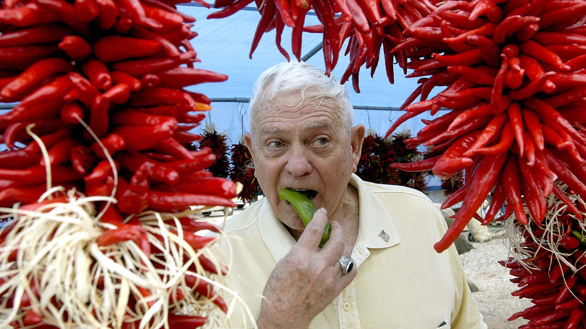 FILE - In this Aug. 30, 2008 file photo, framed by ristras, John Trewitt bites into a pod of fresh Hatch green chile, at the Hatch Chile Festival in Hatch, N.M.
