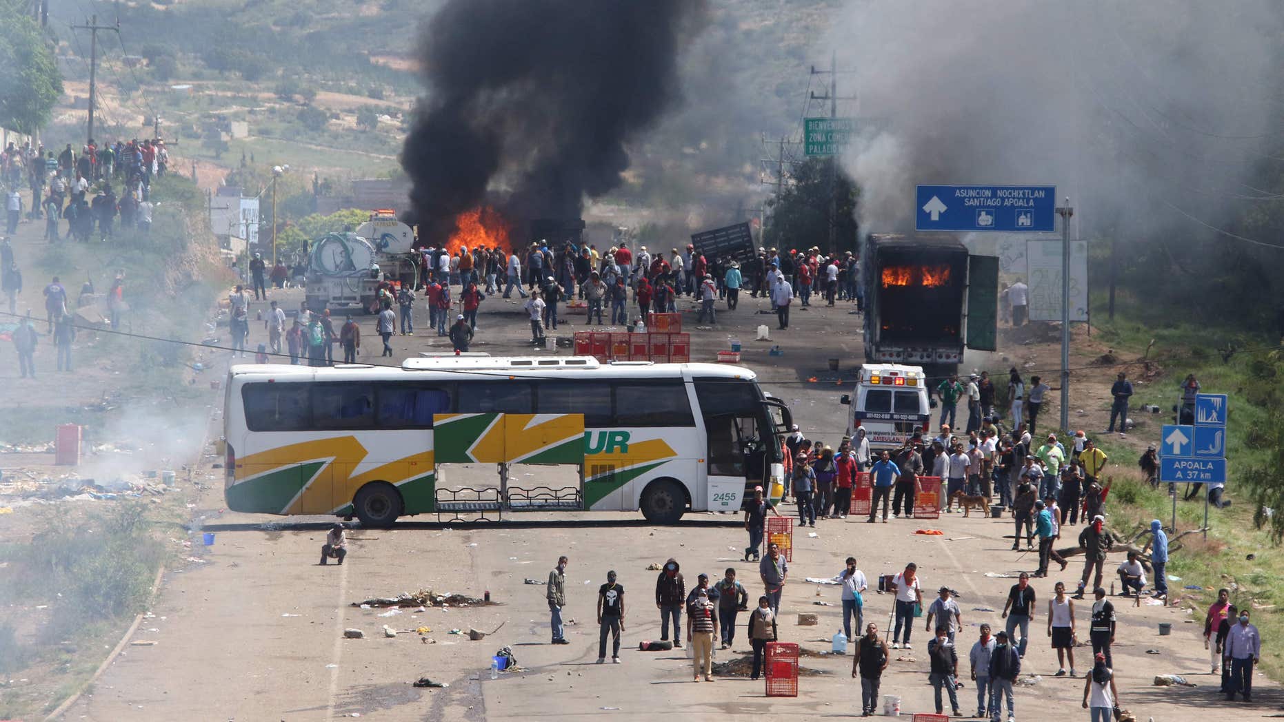 June 19, 2016: Protesting teachers who were blocking a federal highway hold their positions with a passenger bus across the road and burning trucks as they battle with riot police in the state of Oaxaca, near the town of Nochixtlan, Mexico.
