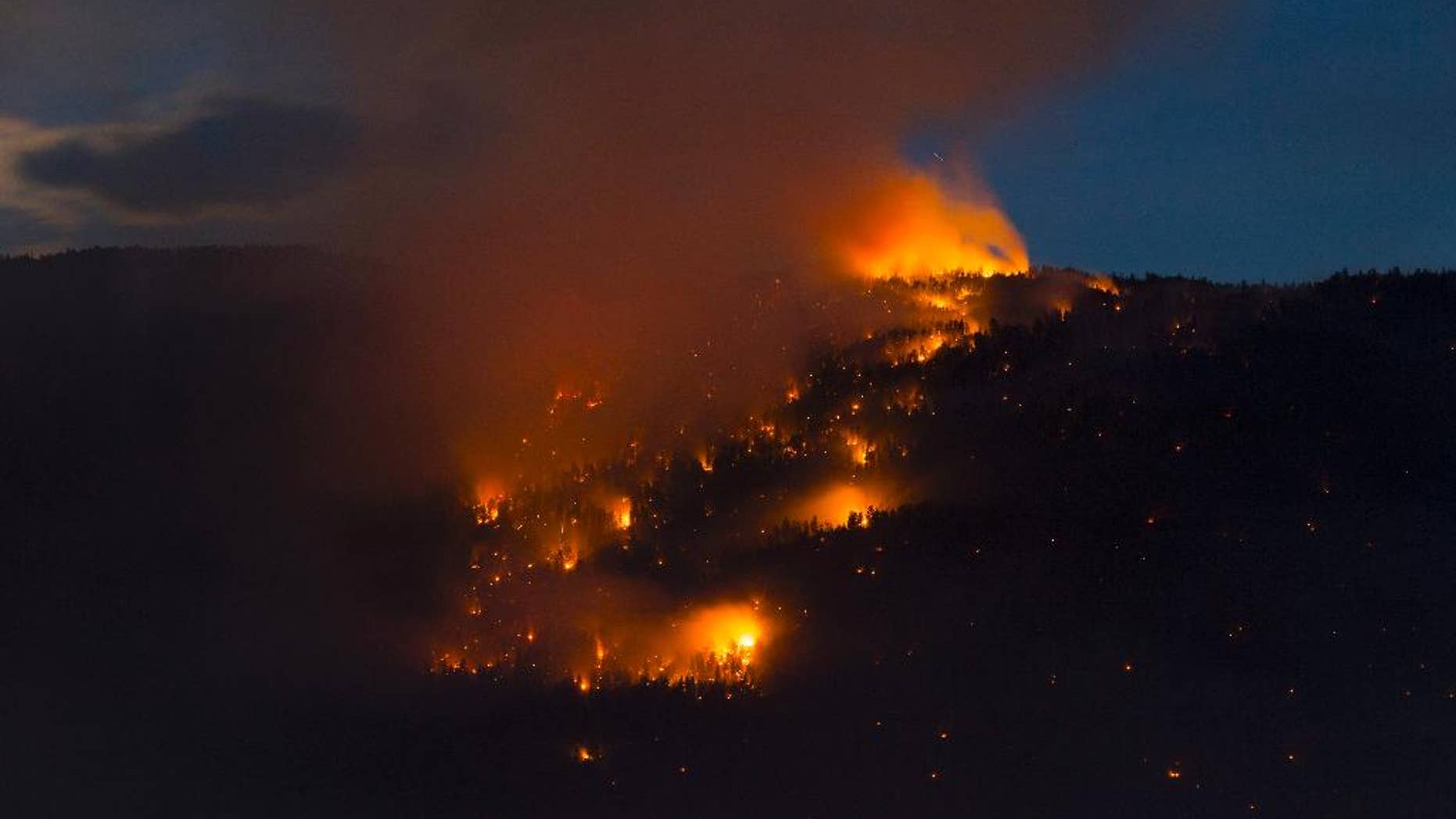 In this photo taken late Wednesday, July 22, 2015, a wildfire lights up a mountainside in West Kelowna, British Columbia. (Jonathan Hayward/The Canadian Press via AP) MANDATORY CREDIT
