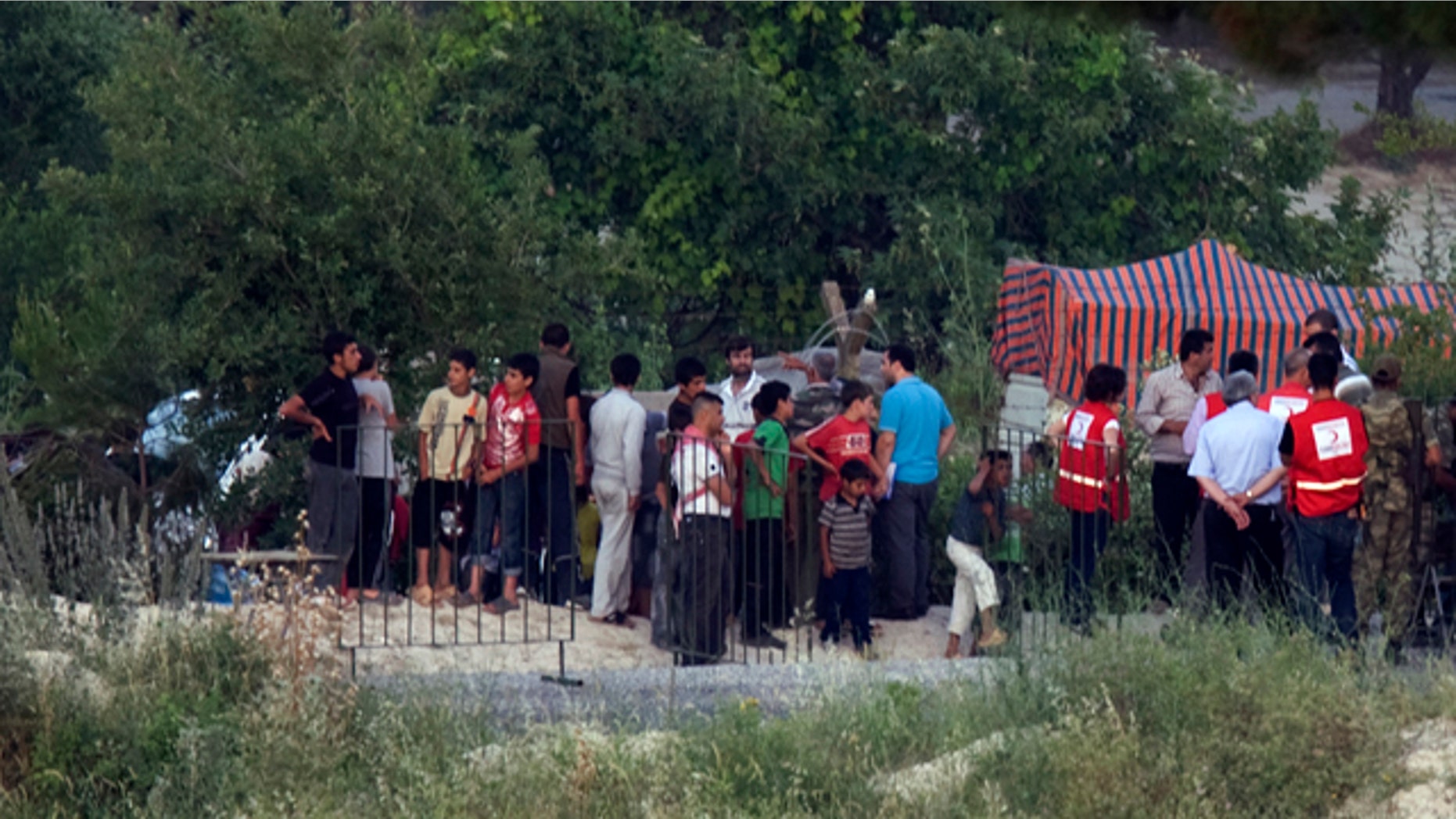 June 22: Officials of Turkey's Red Cresdent distribute free food to Syrians waiting in Syria alongside Turkey-Syria border near the Turkish village of Guvecci in Hatay province, Turkey.