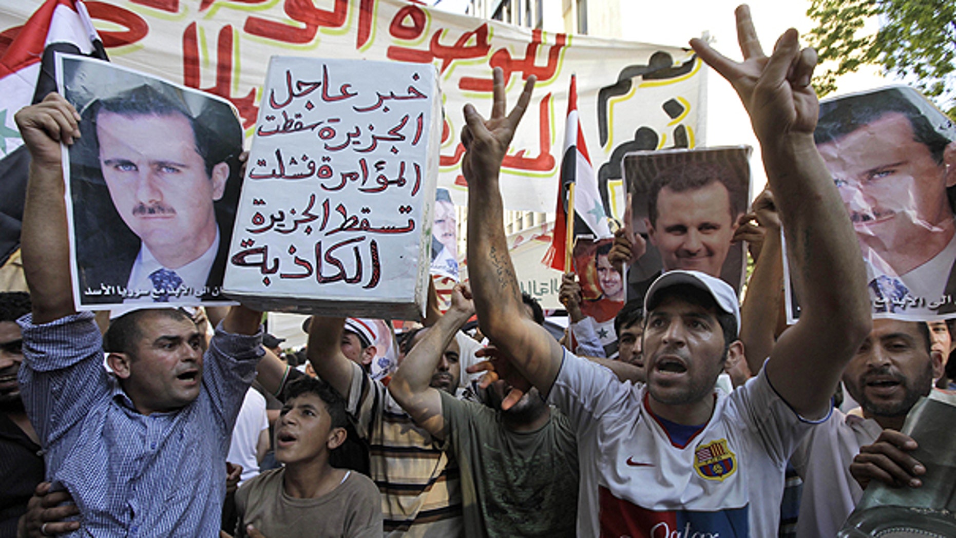 June 24: Lebanese and Syrian protesters shout slogans as they carry pictures of Syrian President Bashar Assad and Syrian flags, during a demonstration to show their support for the Syrian President in front of the Syrian embassy in Beirut, Lebanon.