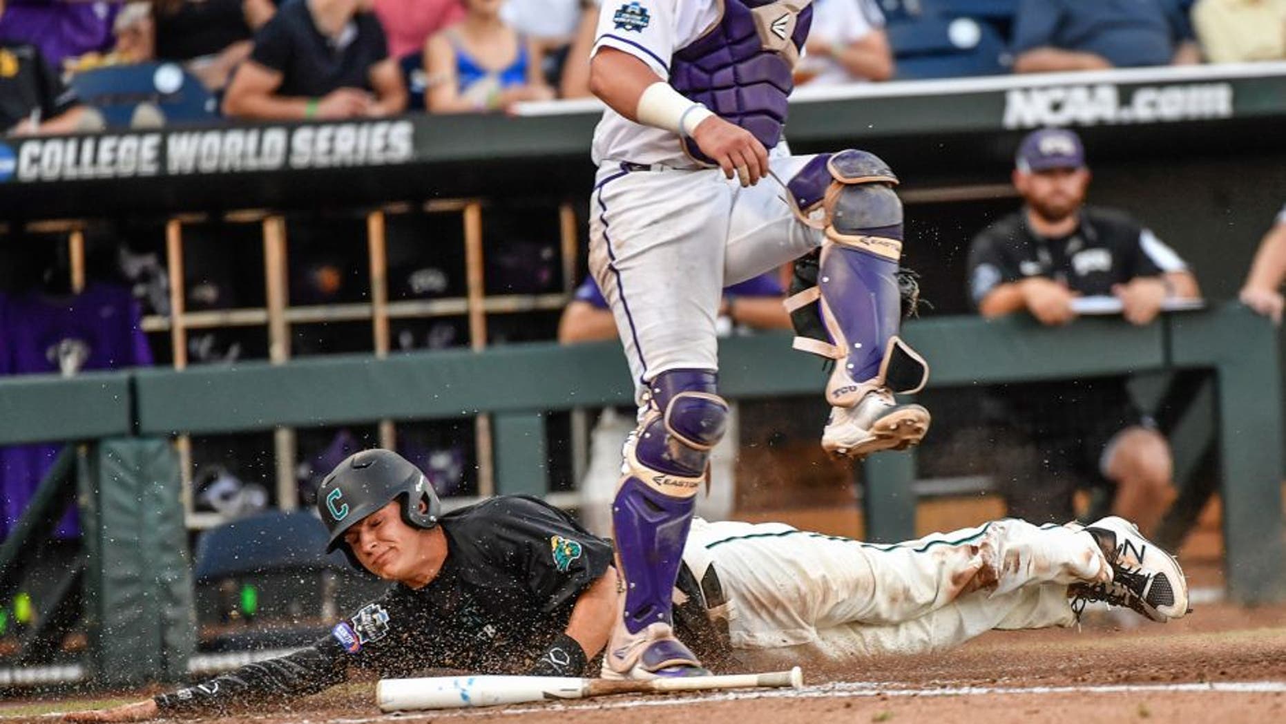 Coastal Carolina's Anthony Marks, bottom, scores behind TCU catcher Evan Skoug on a bunt by Billy Cooke during the third inning of an NCAA College World Series baseball game in Omaha, Neb., Friday, June 24, 2016. (AP Photo/Ted Kirk)