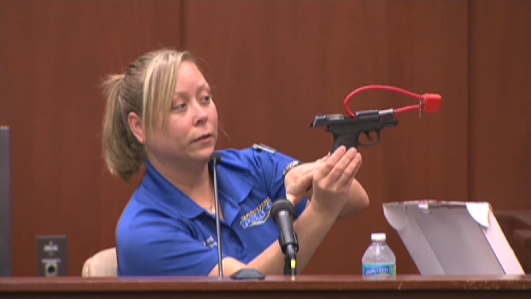 Sanford Police Department crime scene technician Diana Smith holds up a gun belonging to George Zimmerman.